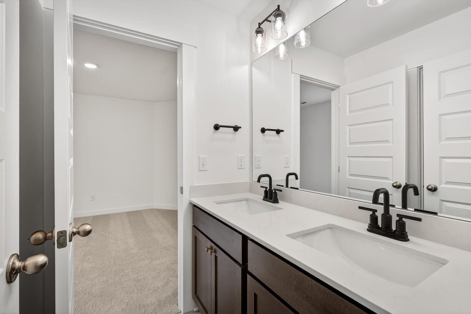 Modern double vanity bathroom with dual sinks, quartz counters, and black faucets in Davidson Homes Ridgeport C, Gallatin TN