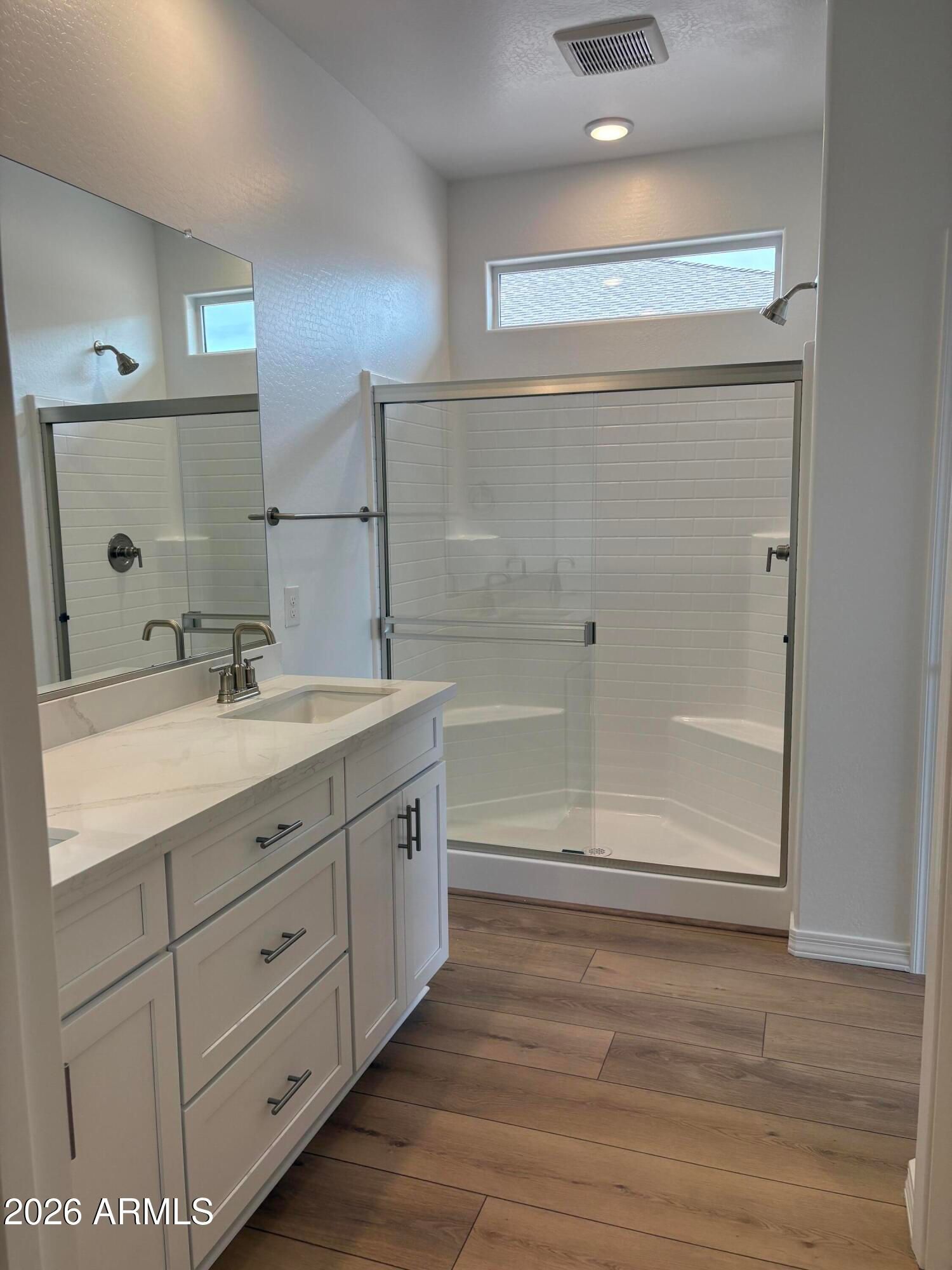 White vanity with quartz countertop and tiled walk-in shower in modern bathroom of Davidson Homes Evergreen B, Cottonwood, AZ