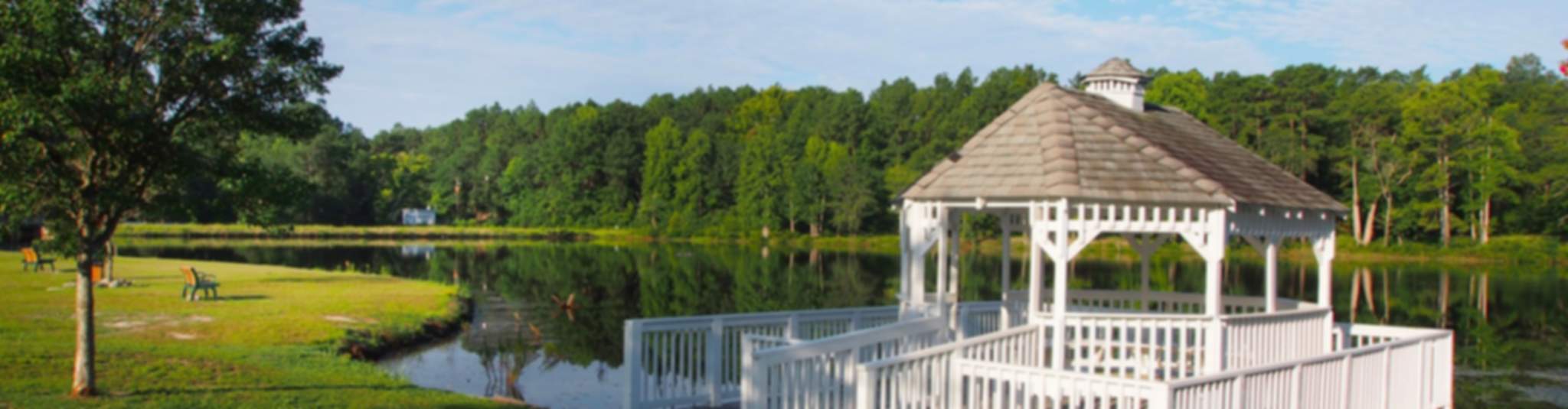 Serene white gazebo on lakeside dock amid lush trees and calm waters in Aberdeen community