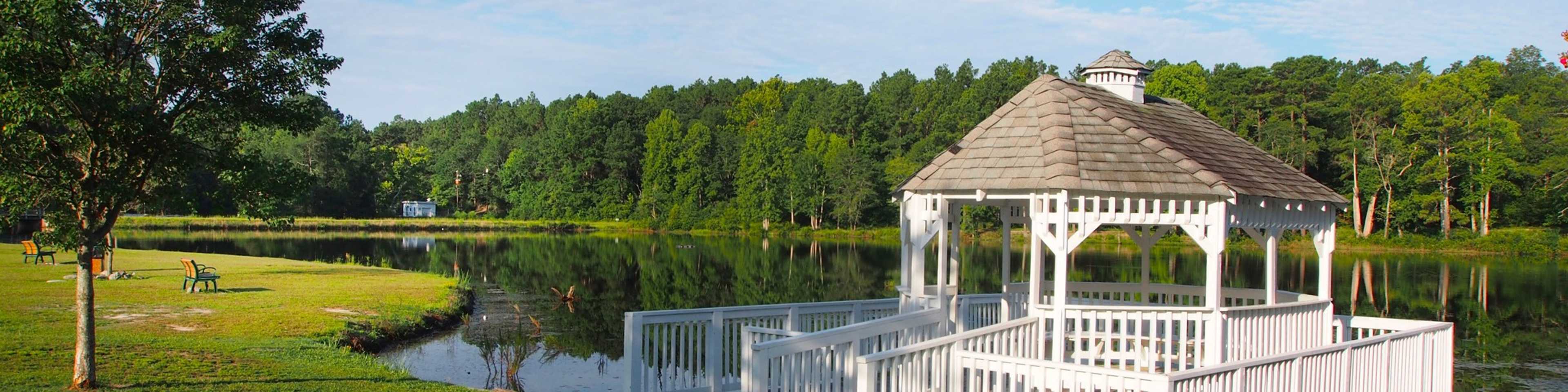Serene white gazebo on lakeside dock amid lush trees and calm waters in Aberdeen community