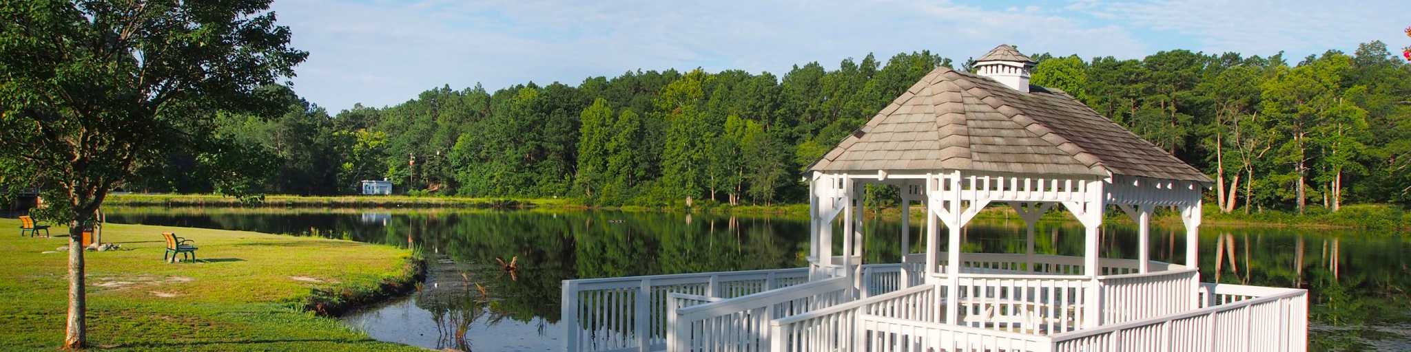 Serene white gazebo on lakeside dock amid lush trees and calm waters in Aberdeen community