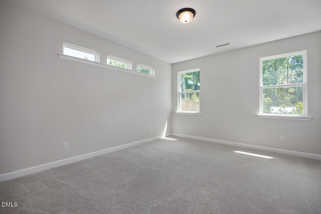 Bright, carpeted bedroom with natural light in The Ashport L floor plan at Sage on North Main, Wake Forest, NC.