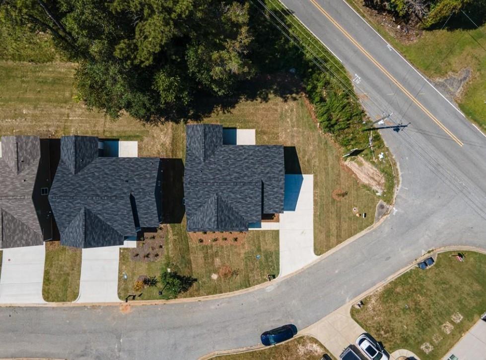 Aerial view of two modern 1-story homes with dark shingle roofs, driveways, and lush green lawns in Summer Vineyard, Phenix City, Alabama