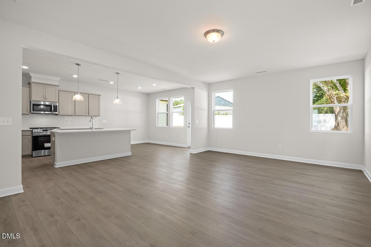 Open-concept living room and kitchen with wood-look flooring in The Gavin A floor plan at Gregory Village, Lillington, NC.