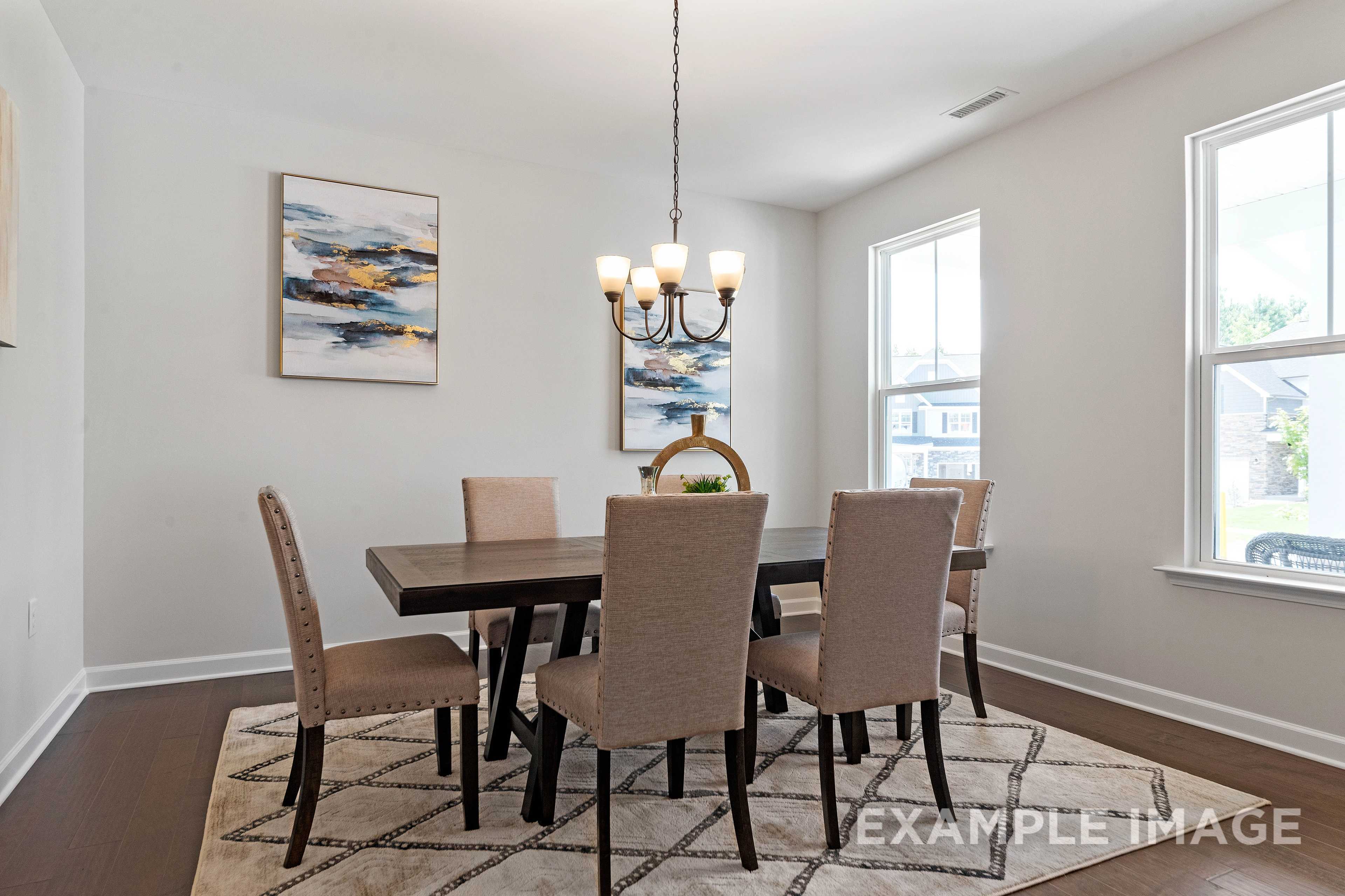 Spacious dining room in The Ash C with wood table, beige upholstered chairs, chandelier, abstract wall art, and large windows
