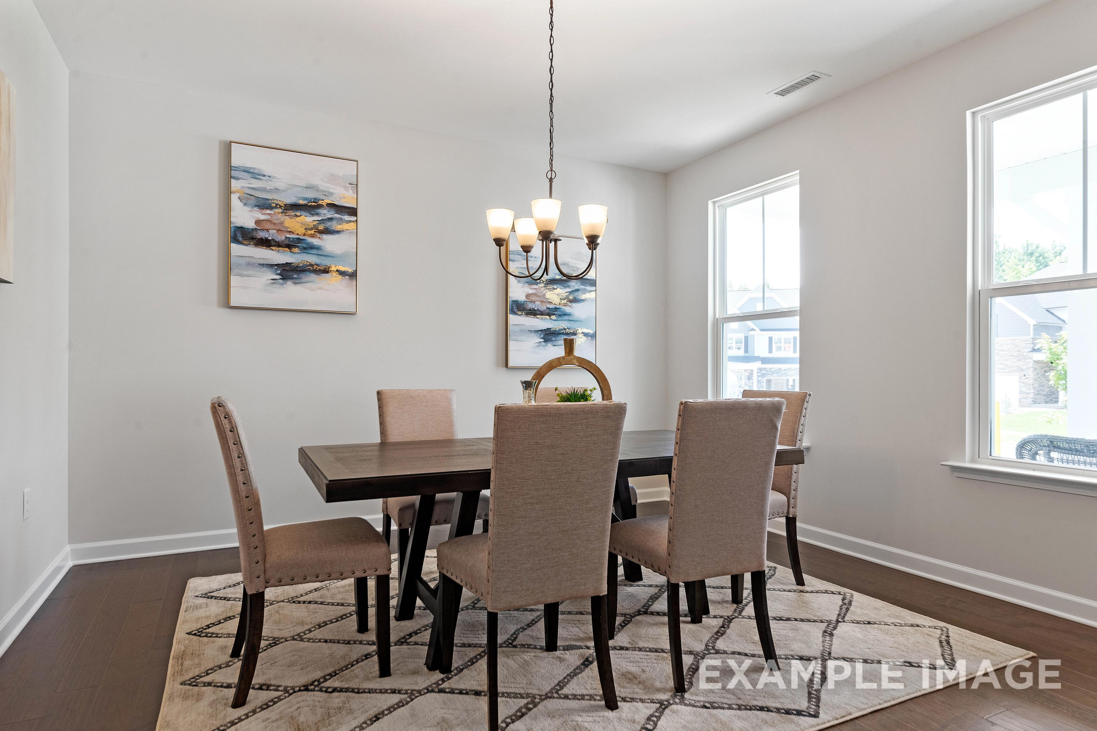 Spacious dining room in The Ash Davidson Homes plan with wooden table, beige upholstered chairs, chandelier, abstract art, large windows