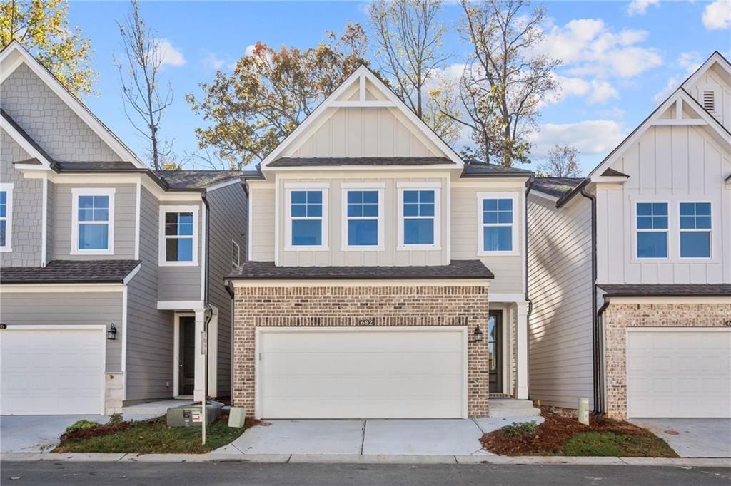 Three 2-story townhomes with 2-car garages, gray siding, and brick accents in The Village at Shallowford, Kennesaw, Georgia - Davidson Homes Marion B