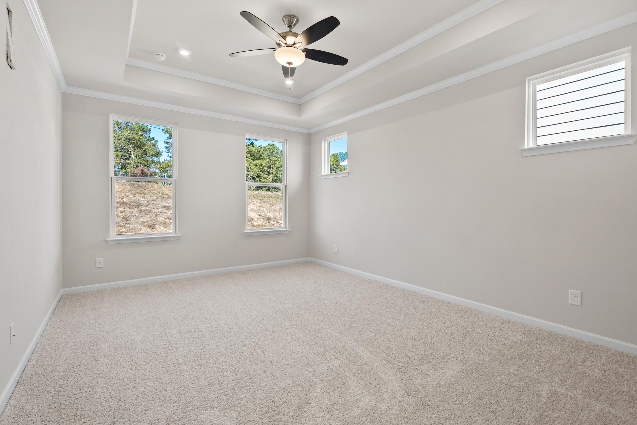Spacious secondary bedroom in The Dawson C with beige walls, large windows, ceiling fan, and carpeted floor