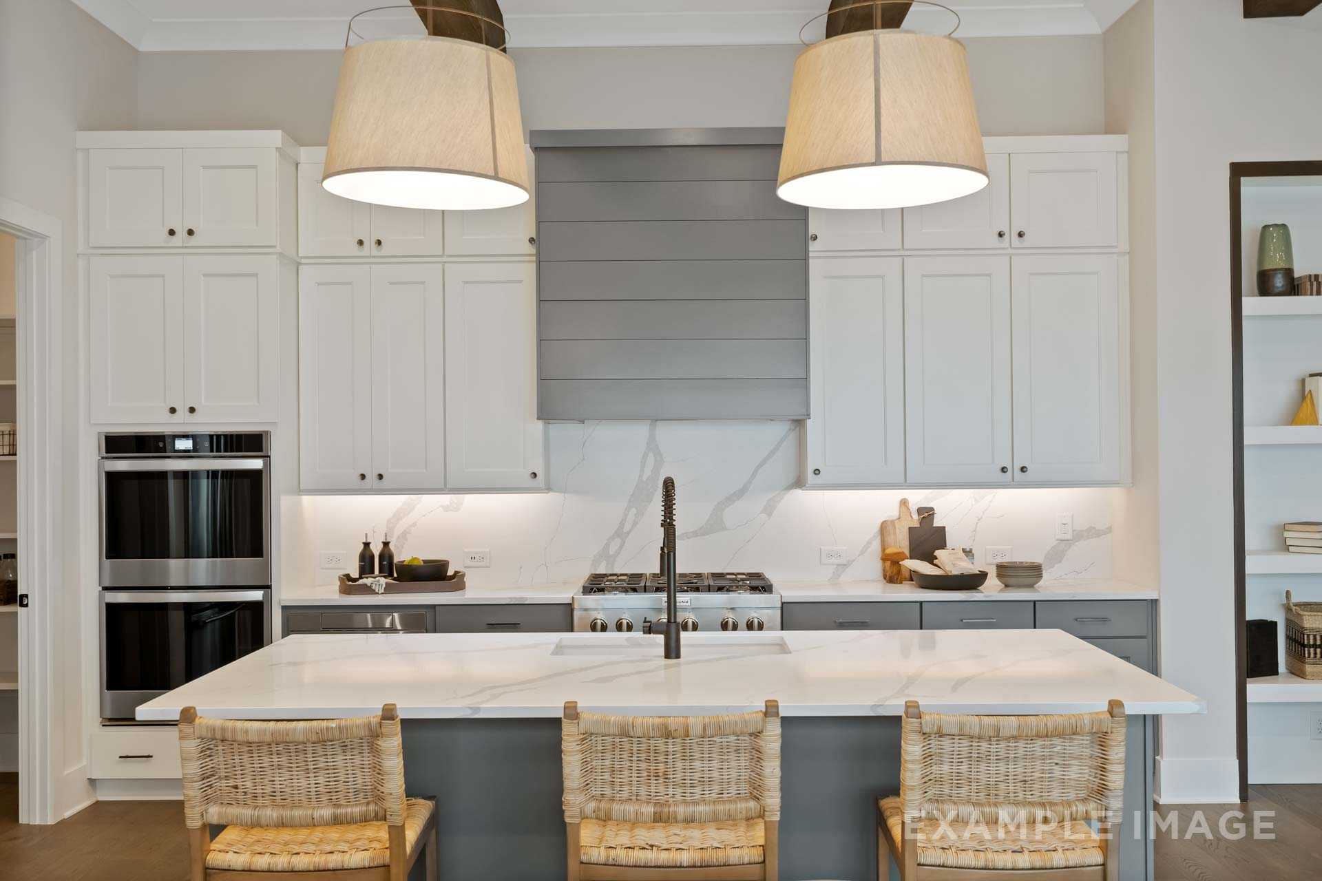 Modern kitchen at Manor Estates in Marietta GA with white shaker cabinets, gray island, quartz counters, and rattan stools