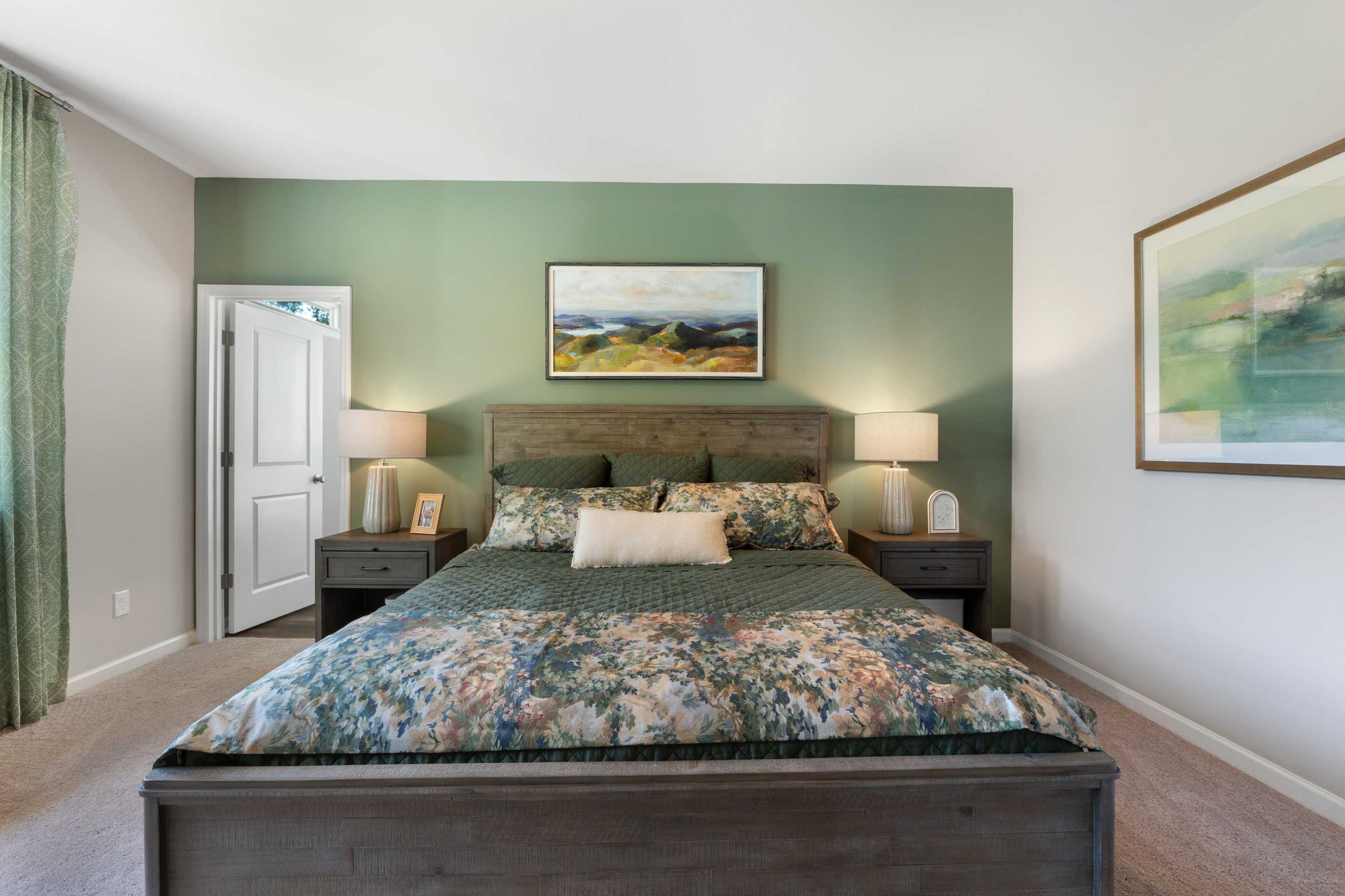 Serene master bedroom in Evergreen Mill, Madison AL with sage green accent wall, wooden bed, floral bedding, and abstract art