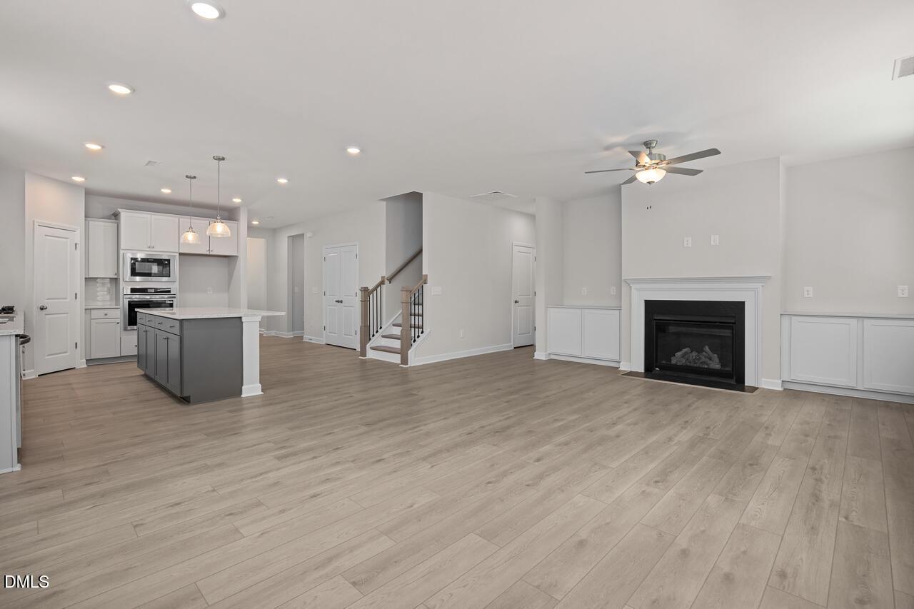 Open-concept living room and kitchen with fireplace in The Ashport G floor plan at Sage on North Main, Wake Forest, NC.