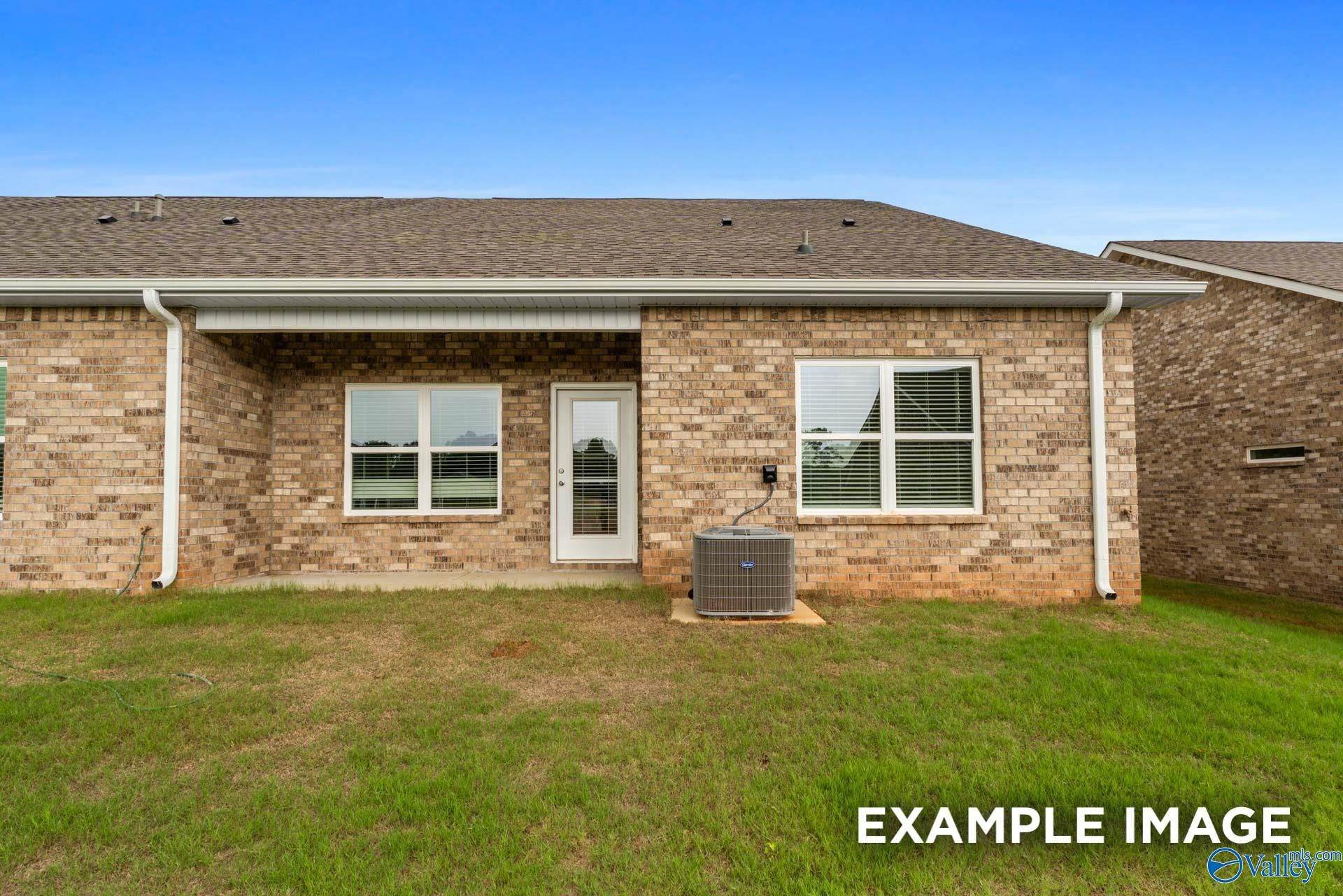 Rear brick single-story home with covered patio, sliding door, large windows, AC unit, and grassy backyard in Decatur, Alabama
