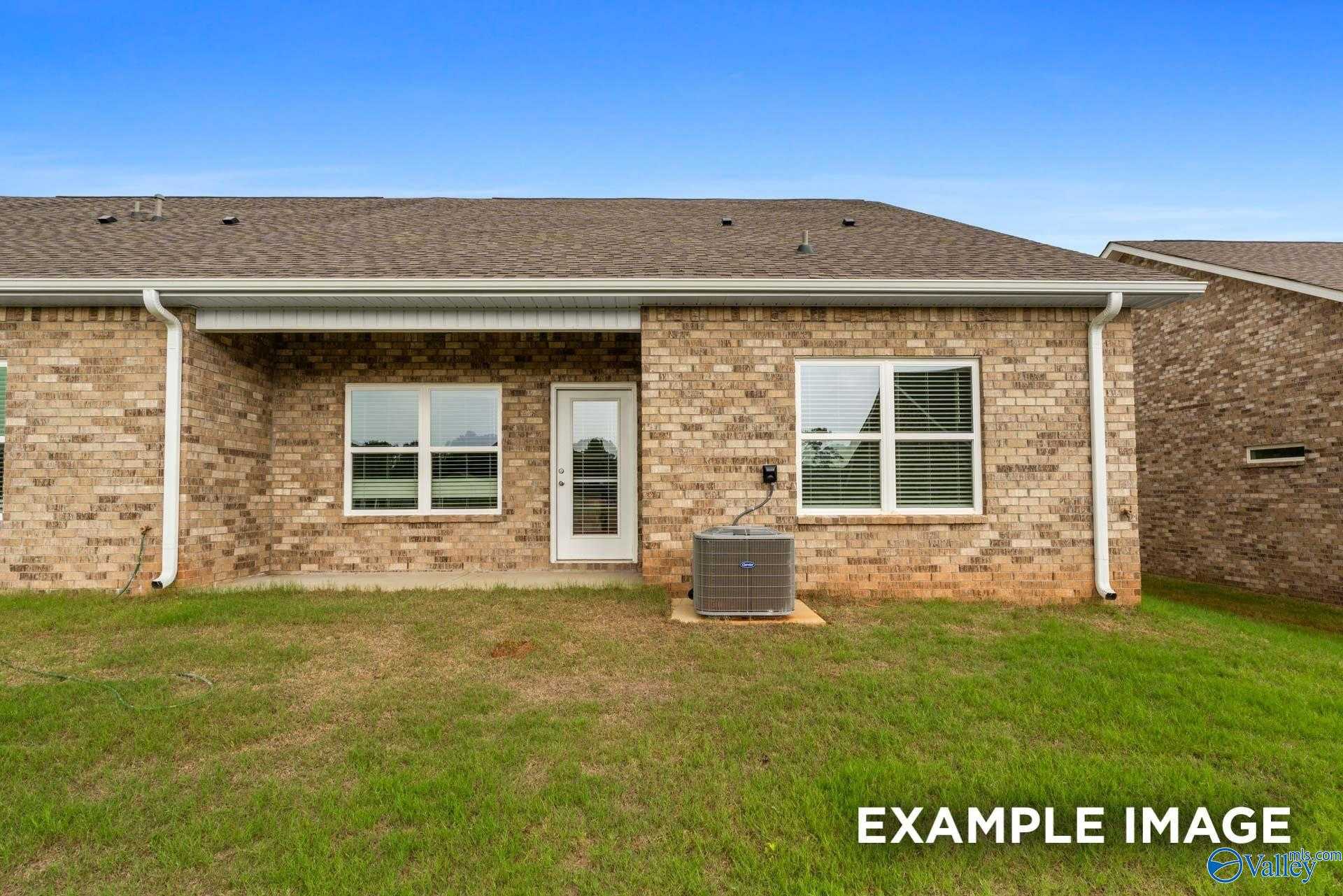 Rear brick single-story home with covered patio, sliding door, large windows, AC unit, and grassy backyard in Decatur, Alabama