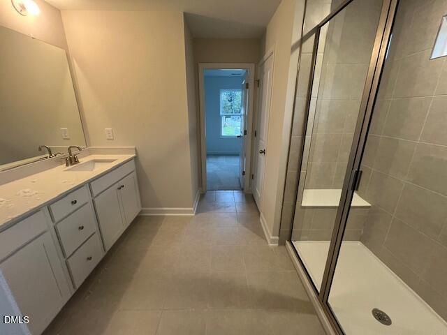 Primary bathroom with white double vanity, tiled walk-in shower, and beige tile floors in Davidson Homes The Willow D, Lillington NC