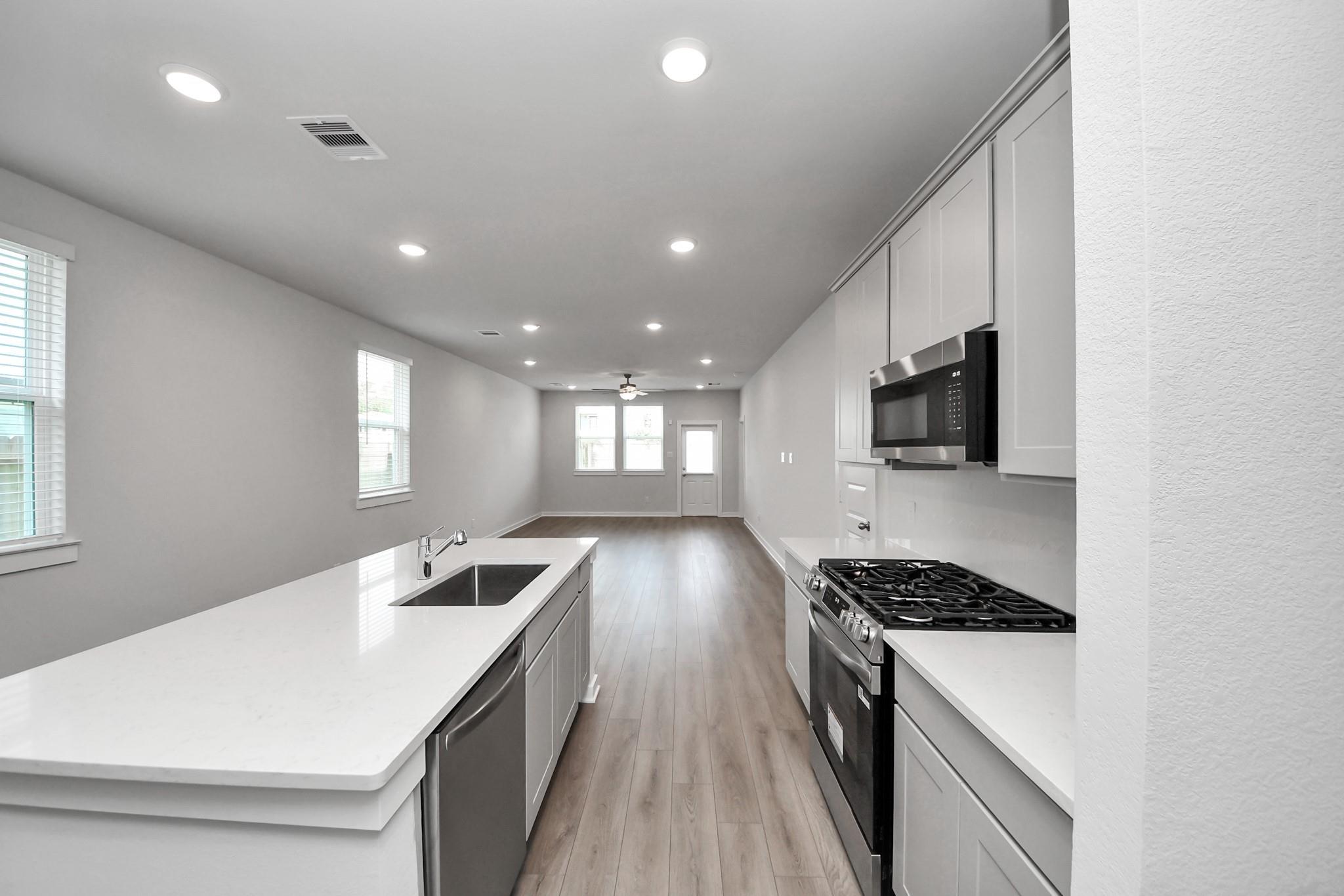 Open-concept kitchen with white island, stainless appliances, and gas range in Davidson Homes Frio F plan, Robins Landing Houston