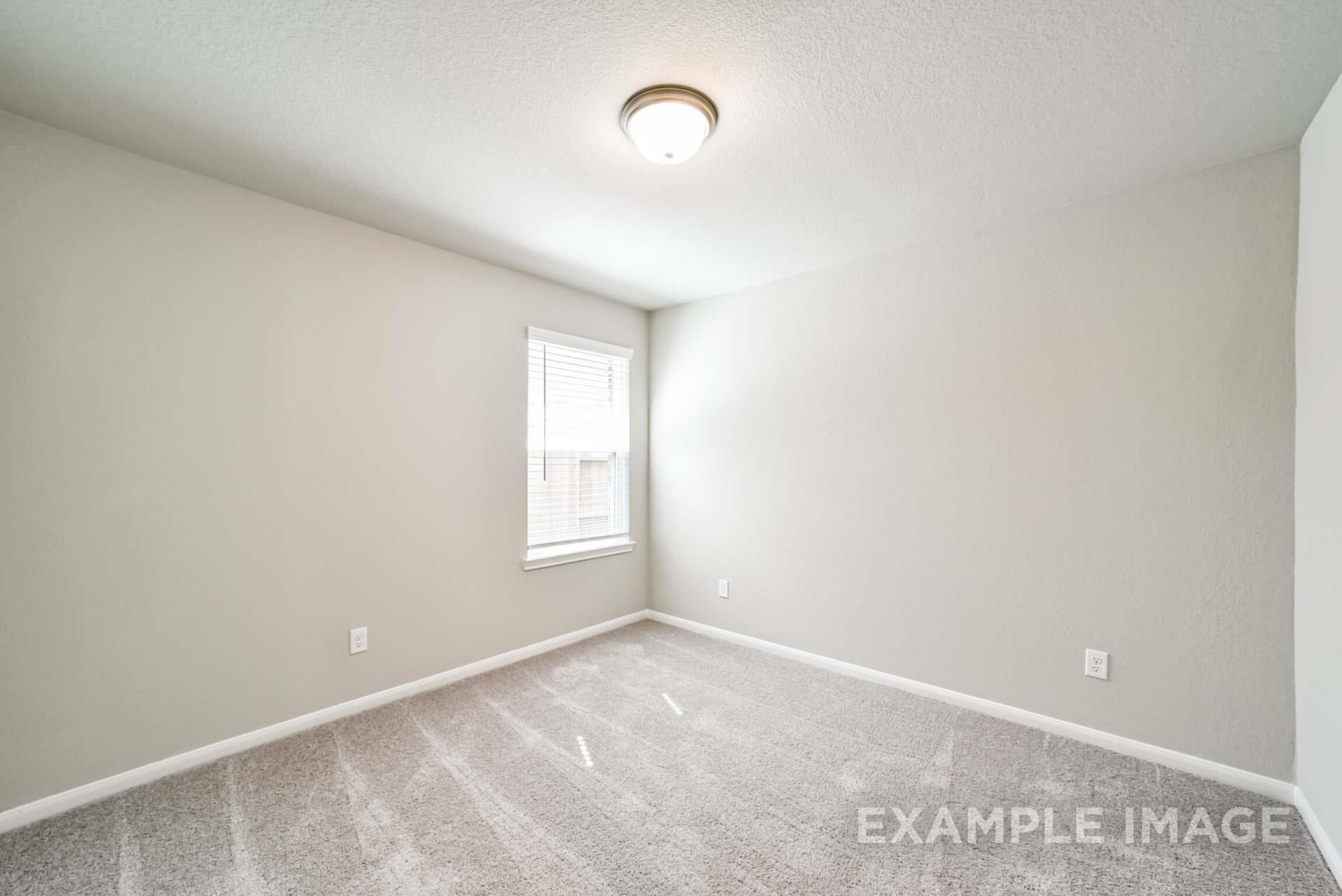 Spacious, neutral-toned bedroom with carpet flooring and window in The Riviera A floor plan by Davidson Homes in Emberly.