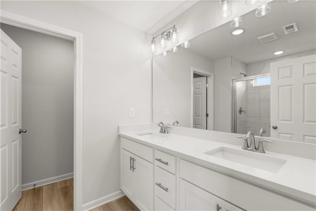Modern primary bathroom with double vanity, white cabinetry, and large mirror in The Wake B plan at Hemingway, Cumming, GA.