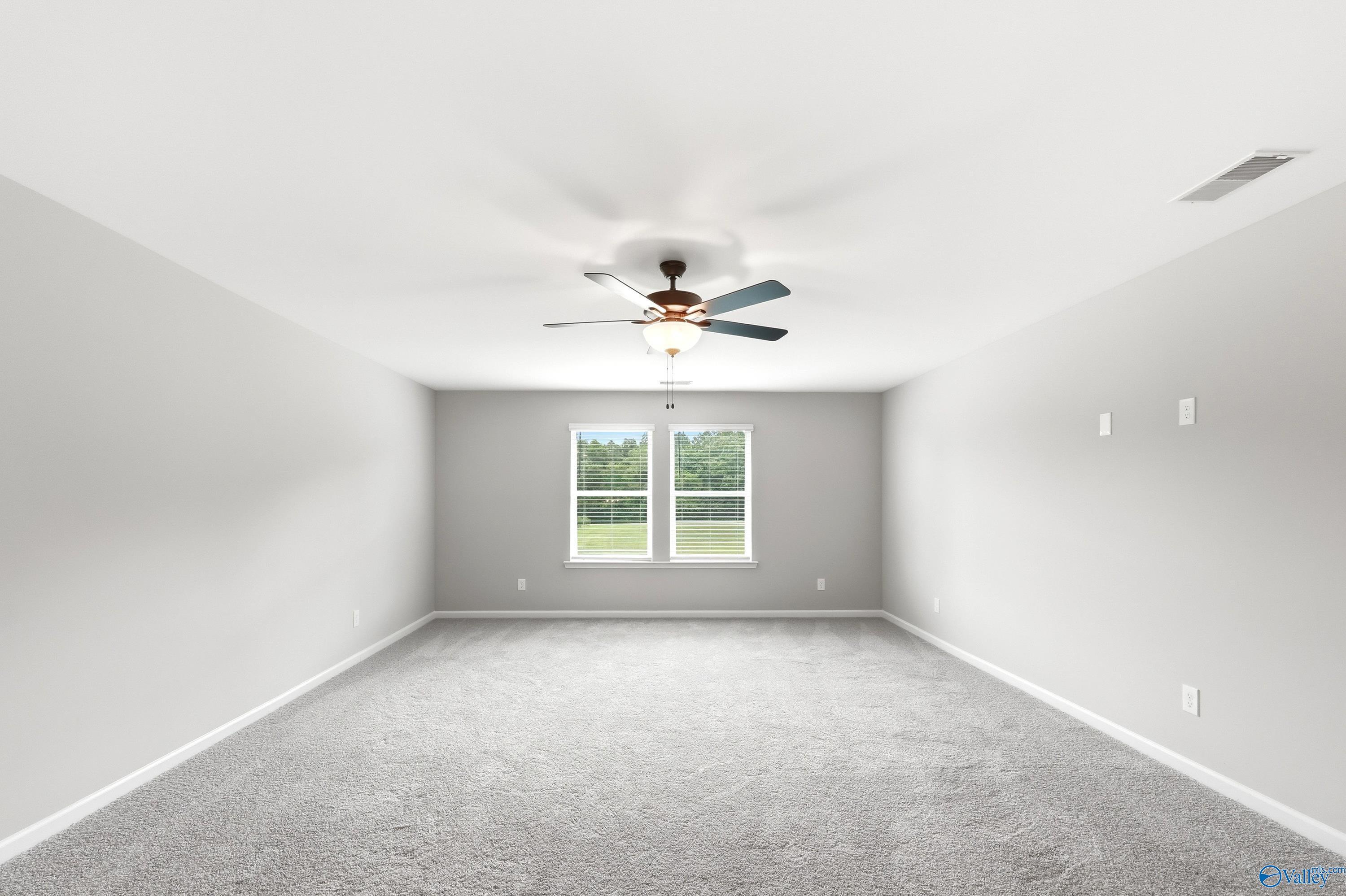 Spacious, carpeted bedroom with ceiling fan and natural light in The Dorado floor plan at Riverton Preserve, Huntsville.