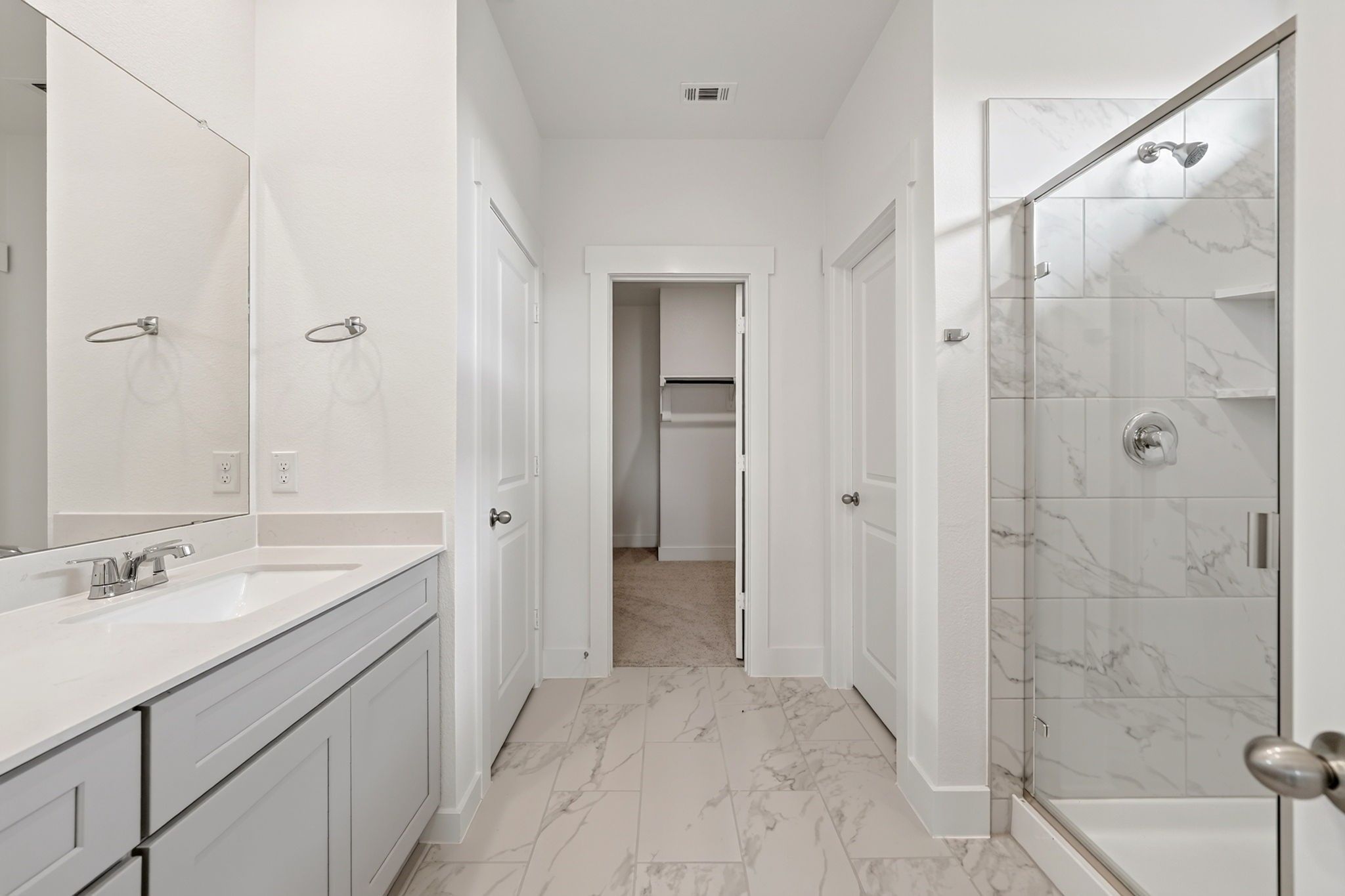 Elegant master bathroom with dual vanity, marble tile shower, and walk-in closet in Davidson Homes The Holly F, Josephine, Texas