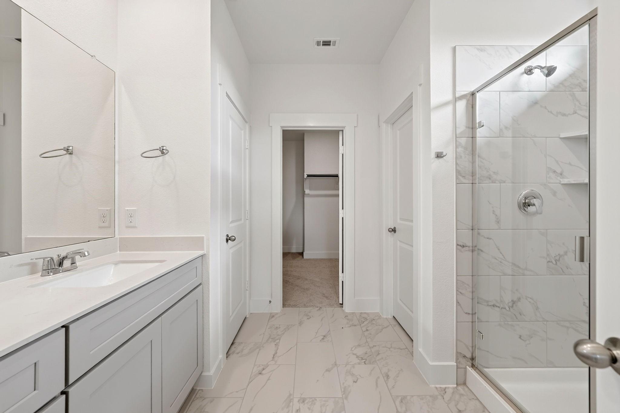 Elegant master bathroom with dual vanity, marble tile shower, and walk-in closet in Davidson Homes The Holly F, Josephine, Texas