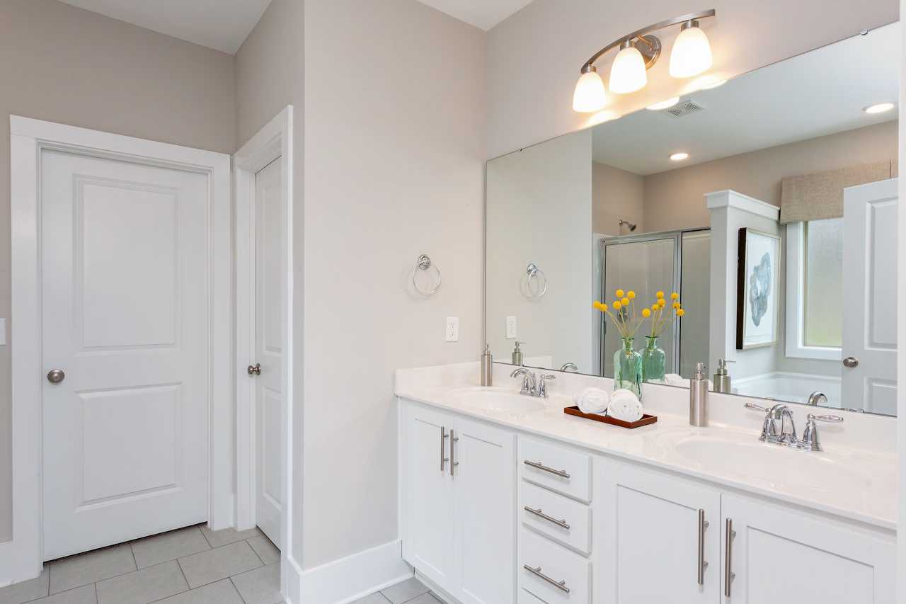 Spacious primary bathroom at Laurenwood Preserve in Madison AL with double white vanity, large mirror, and glass shower