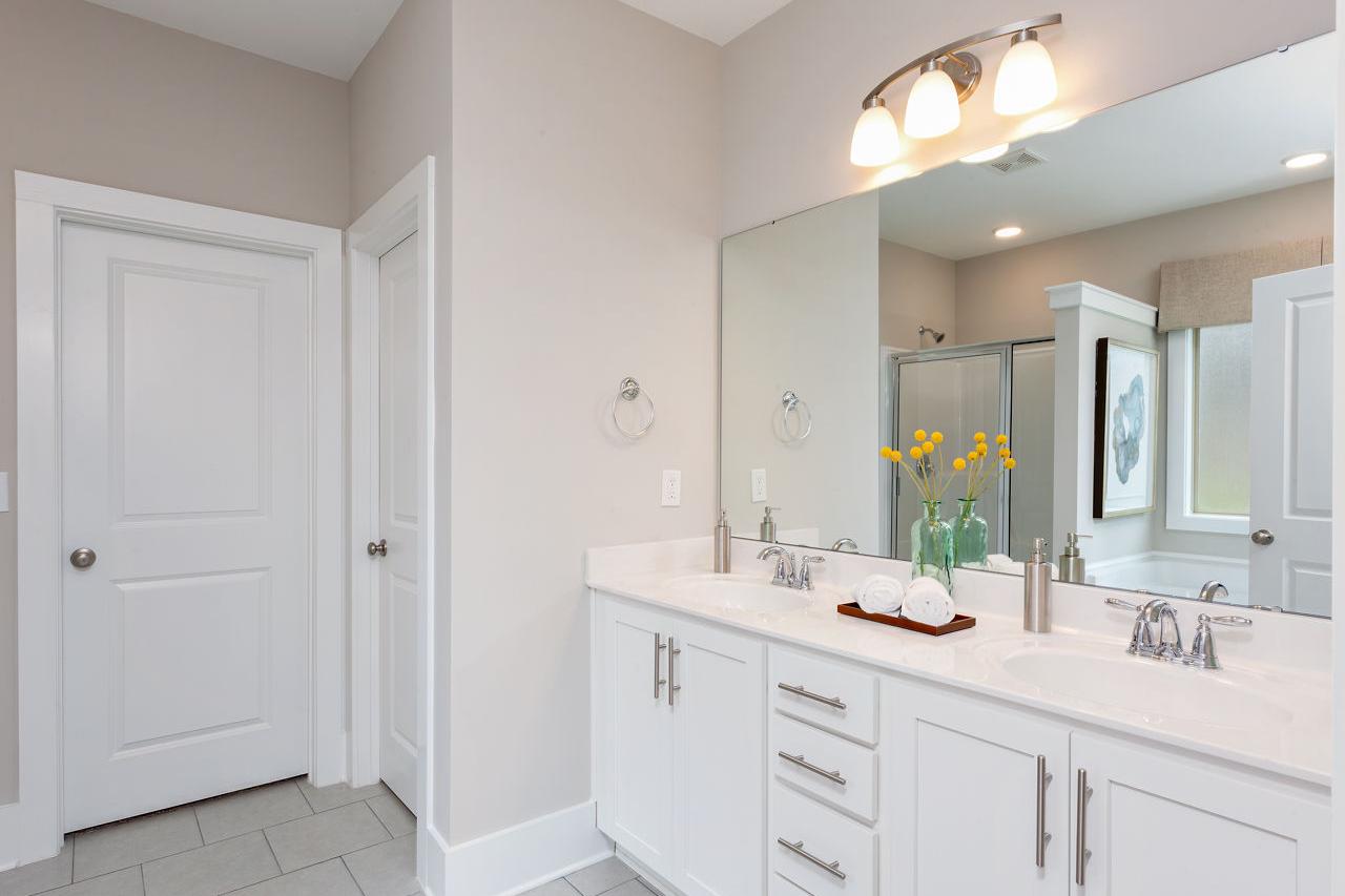 Spacious primary bathroom at Laurenwood Preserve in Madison AL with double white vanity, large mirror, and glass shower