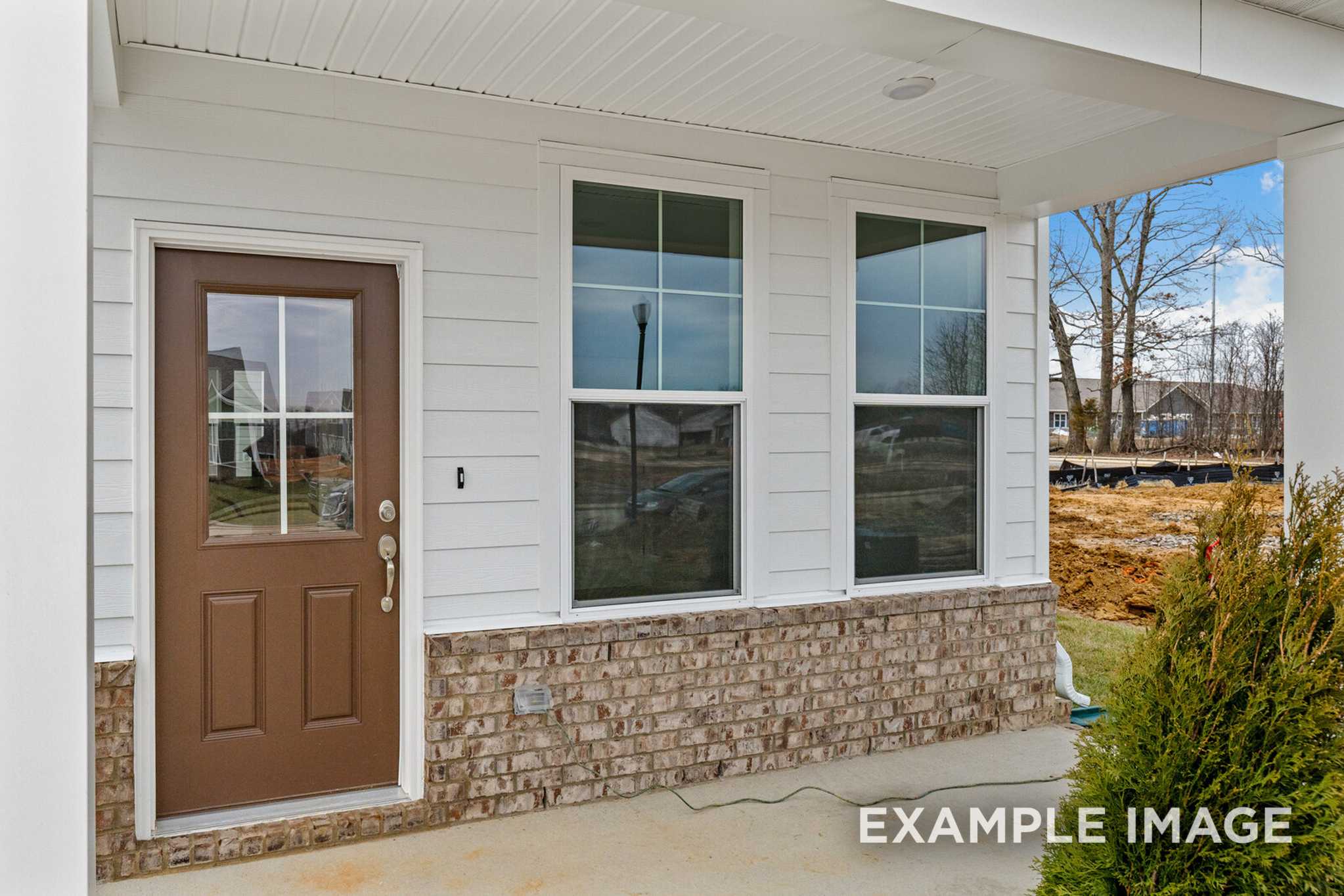 Front elevation of The Logan C two-story home featuring white siding, brick foundation, brown double door, and covered porch