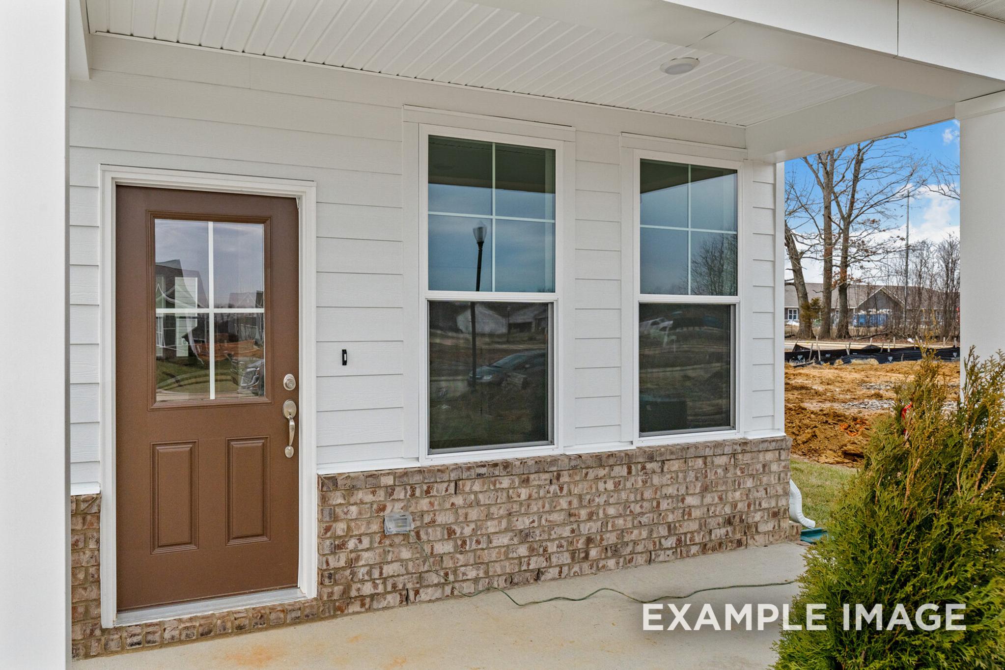 Front elevation of The Logan C two-story home featuring white siding, brick foundation, brown double door, and covered porch