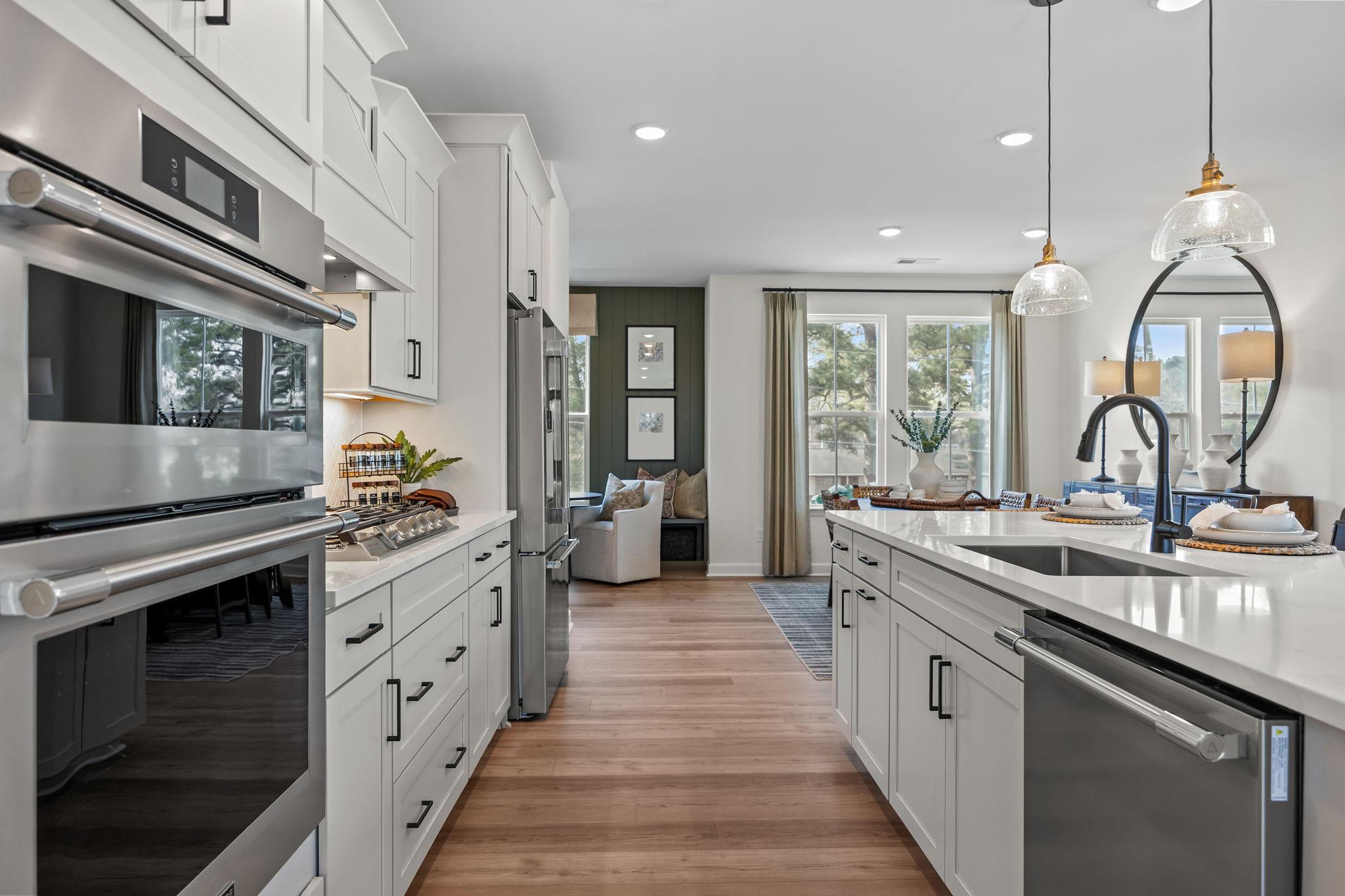 Spacious white kitchen at Forestville Yard Townhomes in Knightdale NC with stainless appliances quartz island and hardwood floors