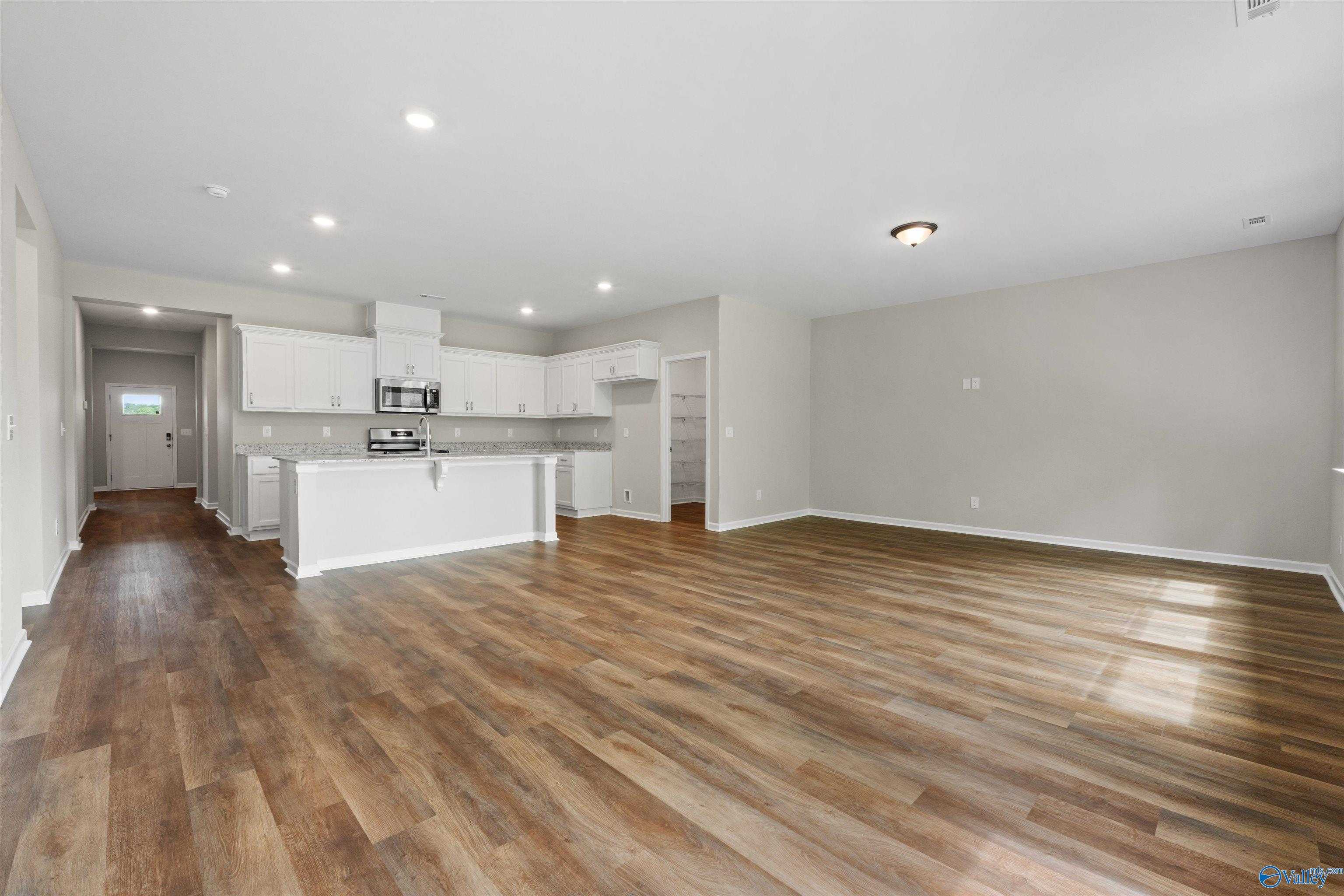Open-concept kitchen with white shaker cabinets, stainless steel appliances, and island in Davidson Homes The Luna, Hazel Green, Alabama