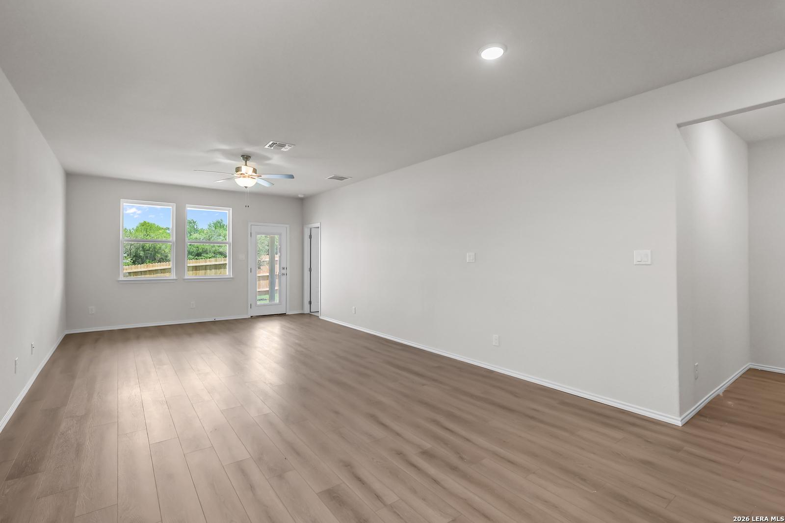 Spacious open-concept living area with wood-style flooring in The San Marcos F by Davidson Homes in San Antonio, Texas.