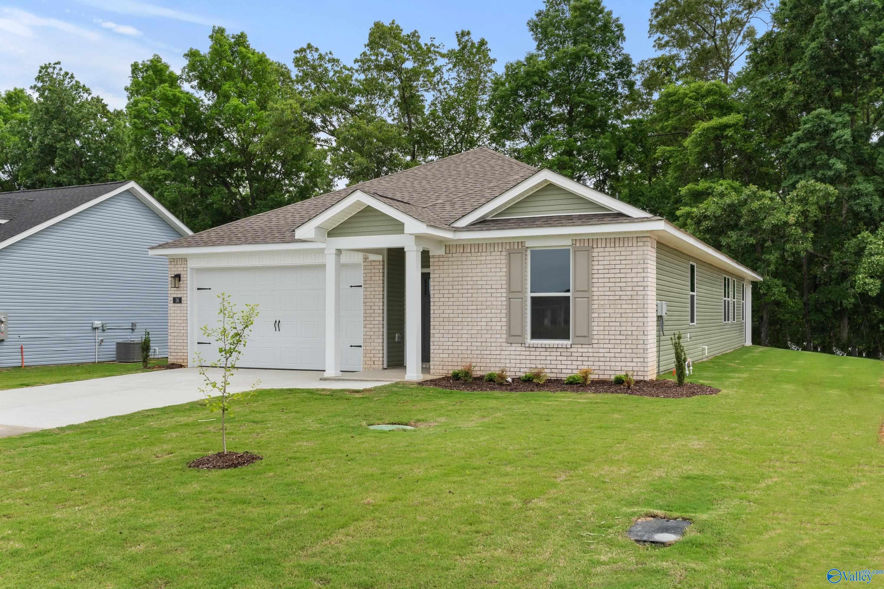 Beige brick single-story home with 2-car garage, covered porch, and landscaped front yard in Bailey Park, Fayetteville, Tennessee - Davidson Homes The Aurora