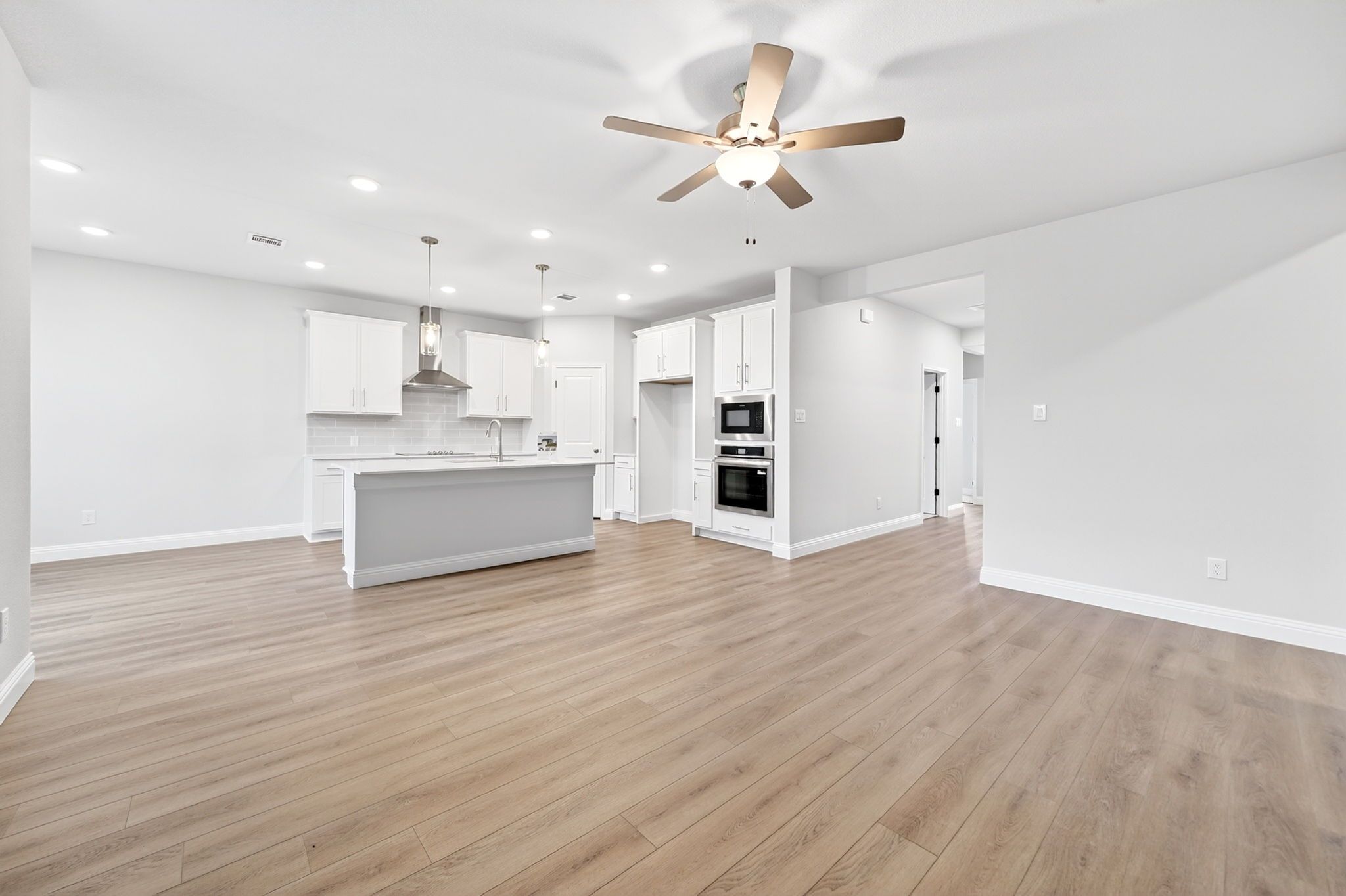 Open-concept kitchen in The Redbud featuring a large island, modern white cabinetry, and stainless steel appliances.