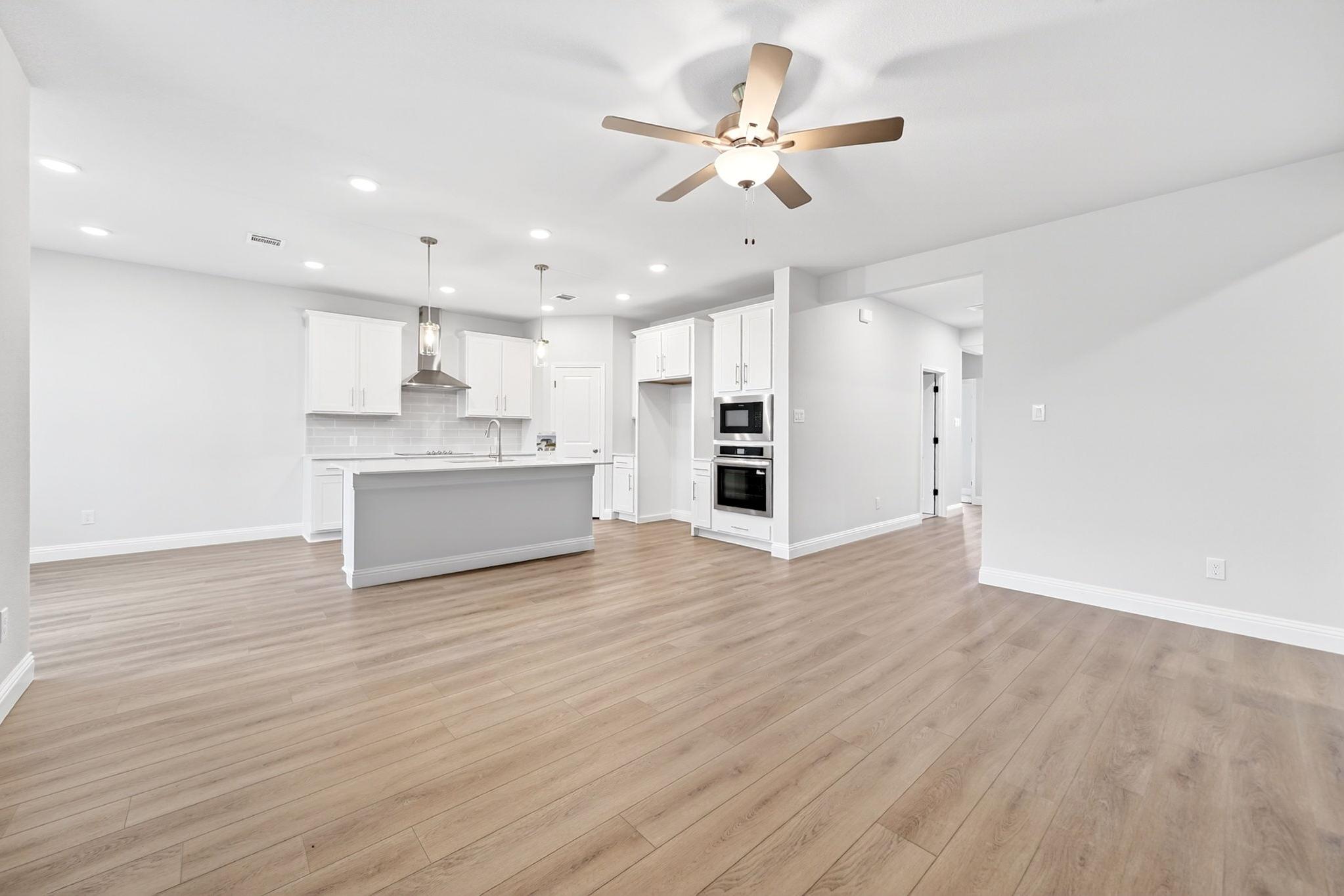 Open-concept kitchen in The Redbud featuring a large island, modern white cabinetry, and stainless steel appliances.