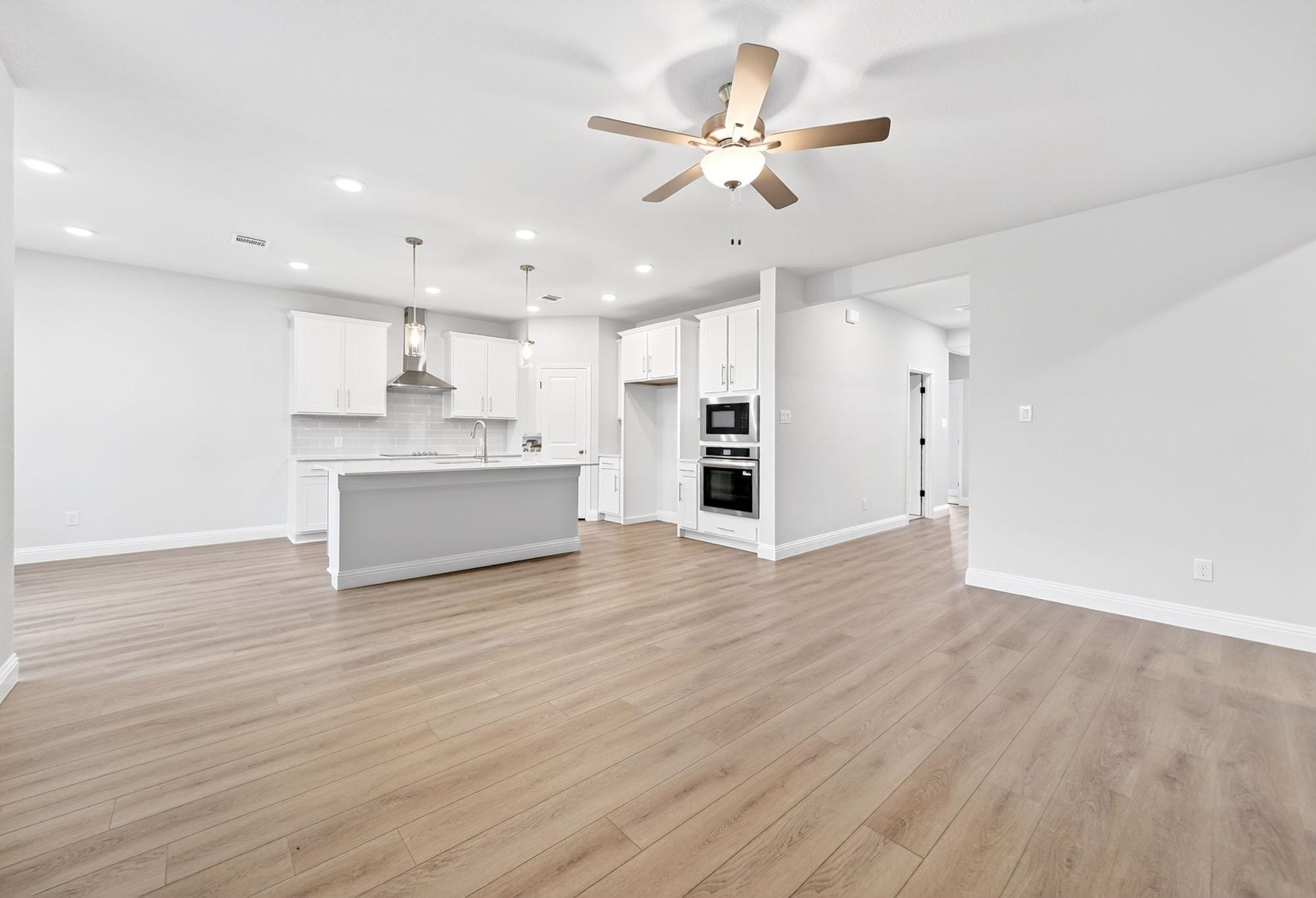 Open-concept kitchen in The Redbud featuring a large island, modern white cabinetry, and stainless steel appliances.