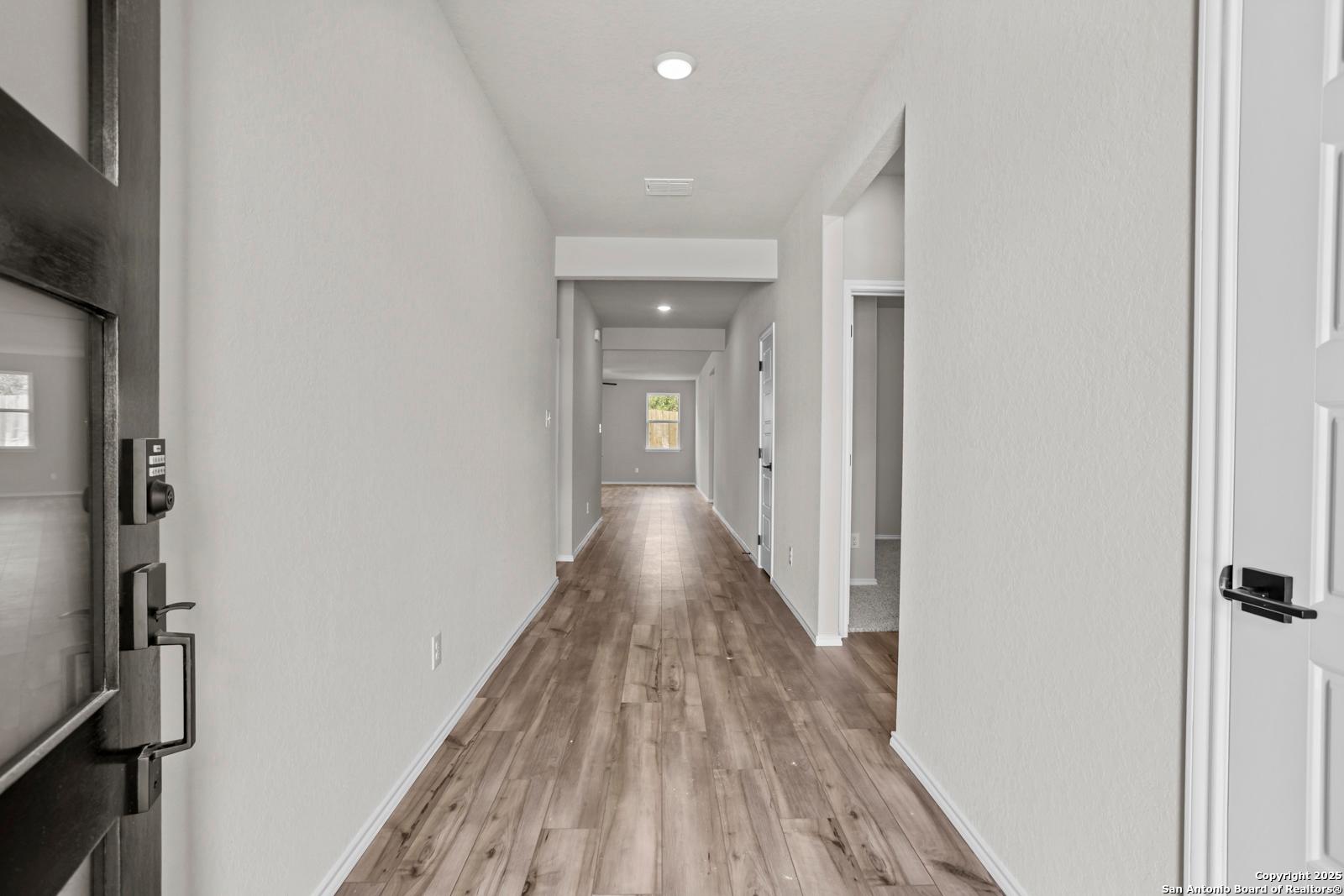 Elegant hallway with hardwood floors and white walls in The Daphne G 3-bedroom home by Davidson Homes, San Antonio, Texas