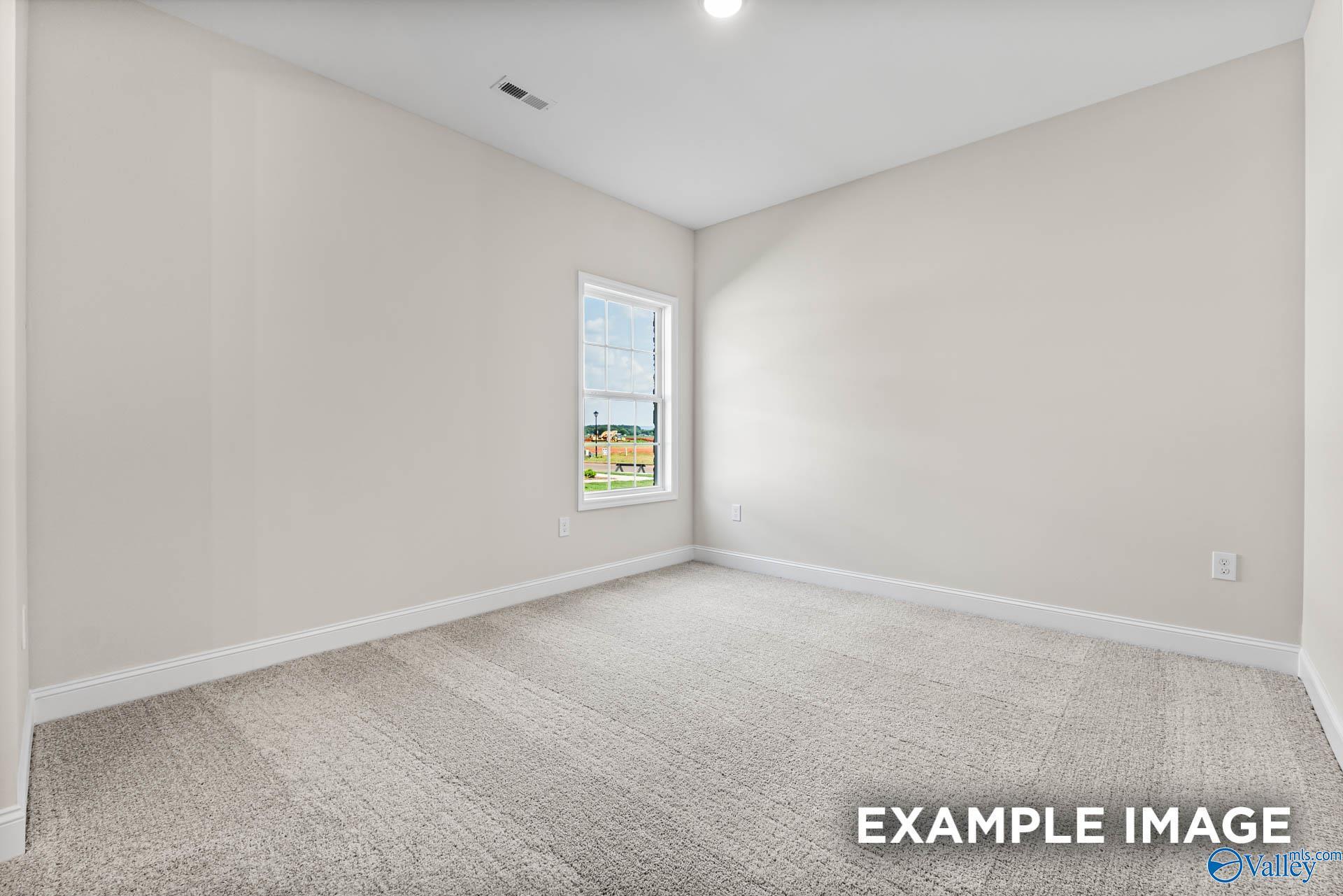 Bright secondary bedroom with large window, beige walls, and neutral carpet in Davidson Homes The Finleigh, Huntsville, Alabama
