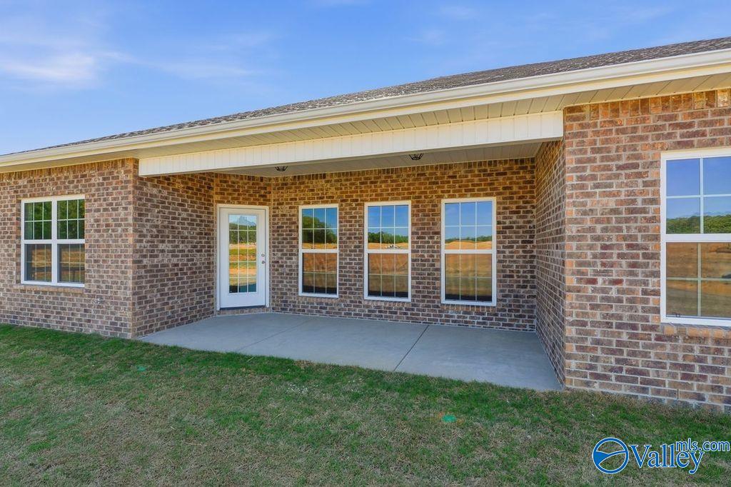 Brick exterior of Davidson Homes The Harrison: large windows, glass door, covered concrete patio, green lawn in Cain Park, Hartselle AL