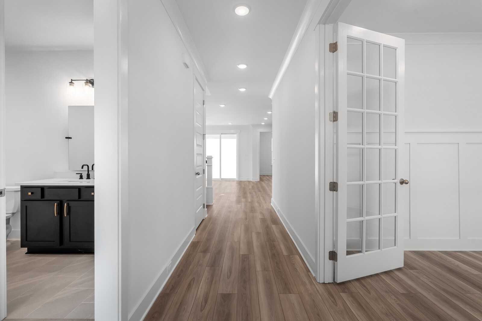 Bright hallway with hardwood floors, modern bathroom vanity, and glass French doors in The Hathaway floor plan, Murfreesboro, TN