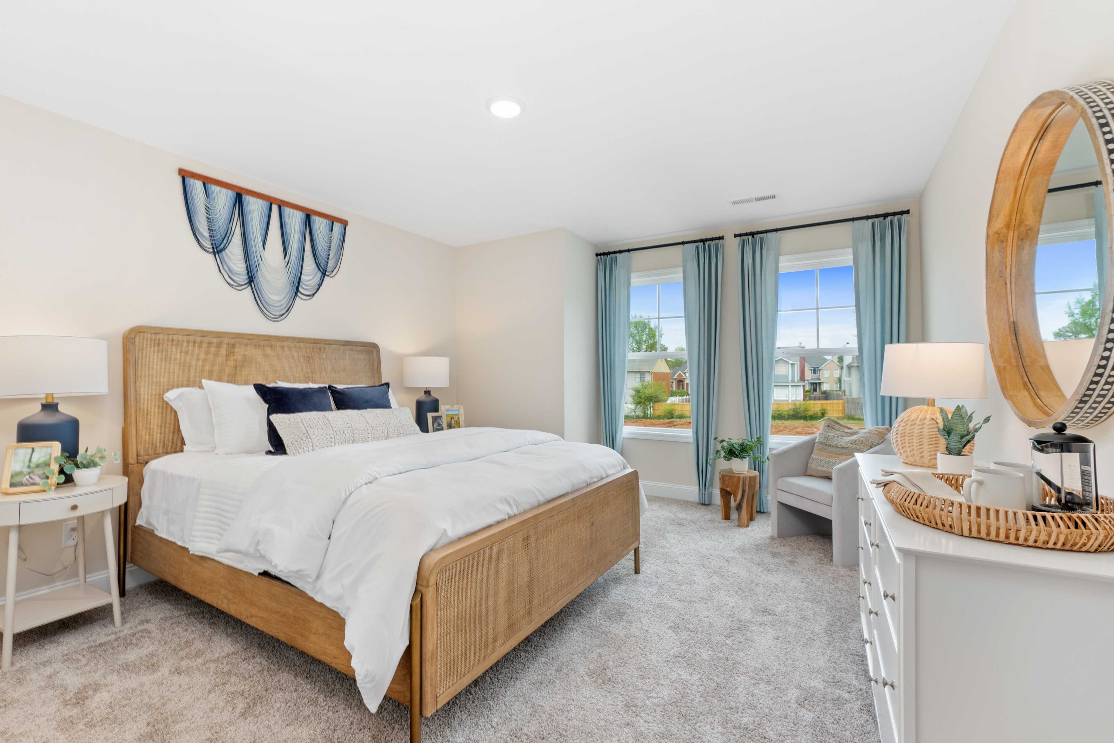Spacious master bedroom at Pavilion in Huntsville AL with wooden bed frame, blue accents, woven wall art, and natural light