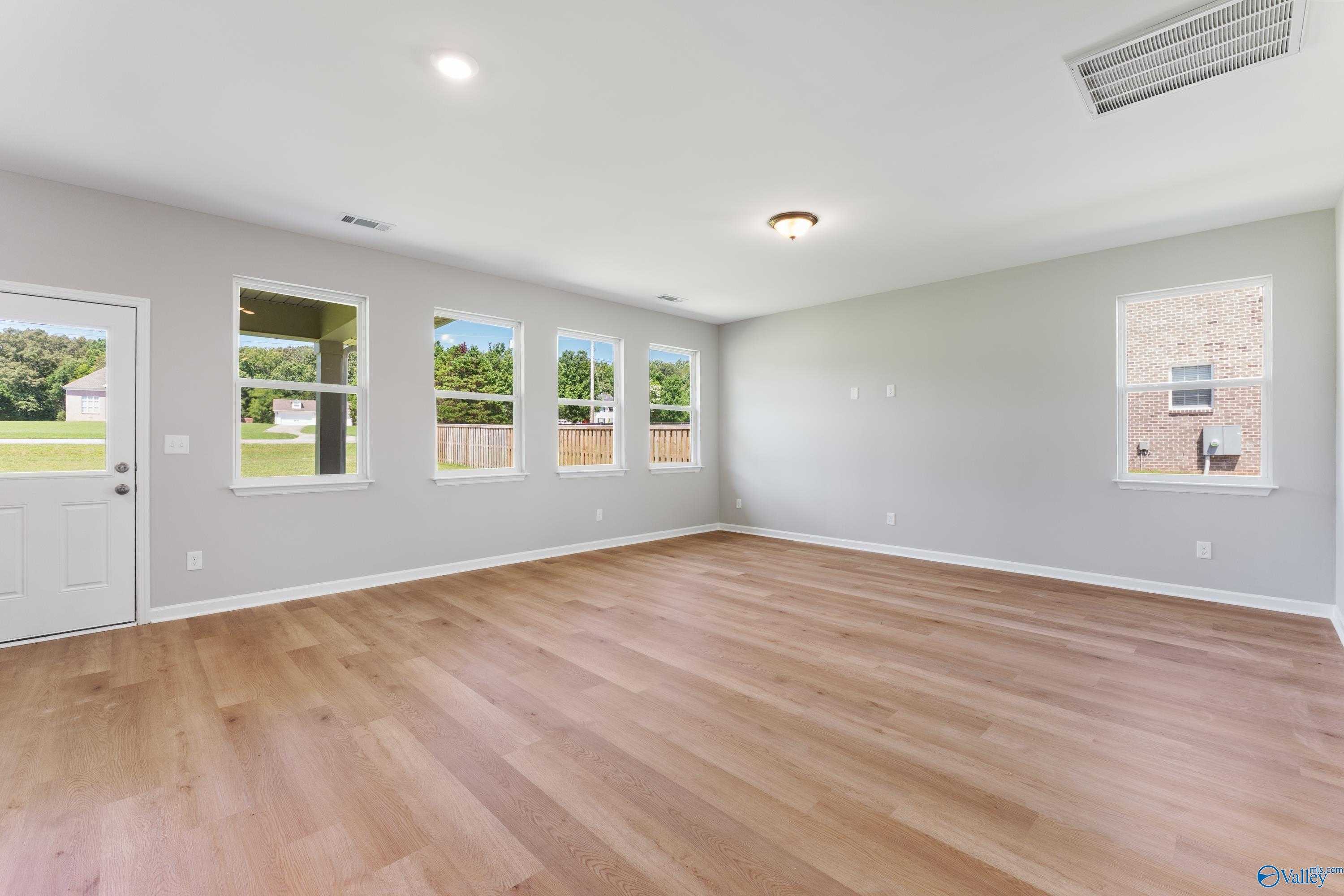 Spacious family room with hardwood floors, gray walls, and large windows to backyard in Davidson Homes The Charm, Huntsville AL