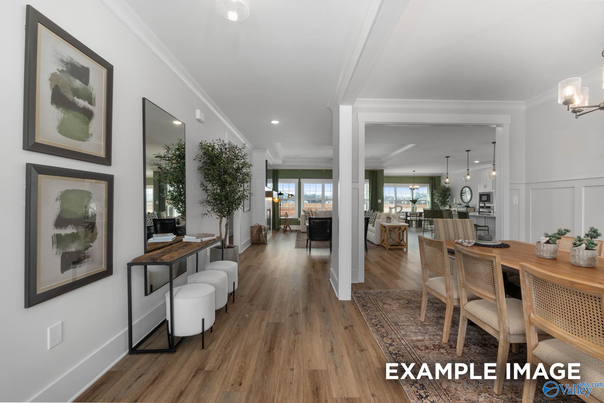 Elegant hallway with abstract art, console table, mirrors, and plants opening to formal dining room in Davidson Homes The Finleigh, Decatur AL