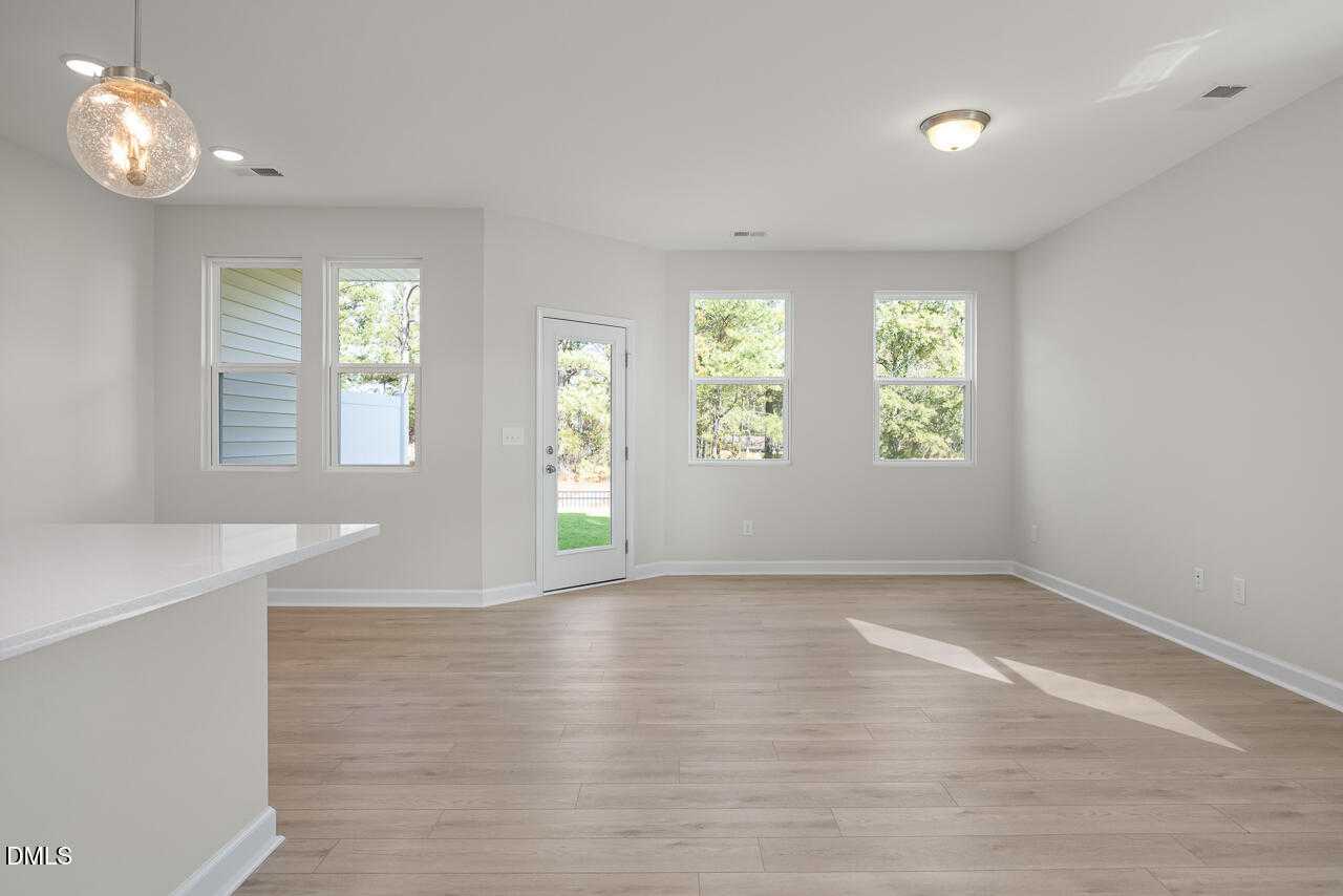 Open-concept living room with white island, hardwood floors, and natural light in Davidson Homes The Graham, Fuquay-Varina, NC