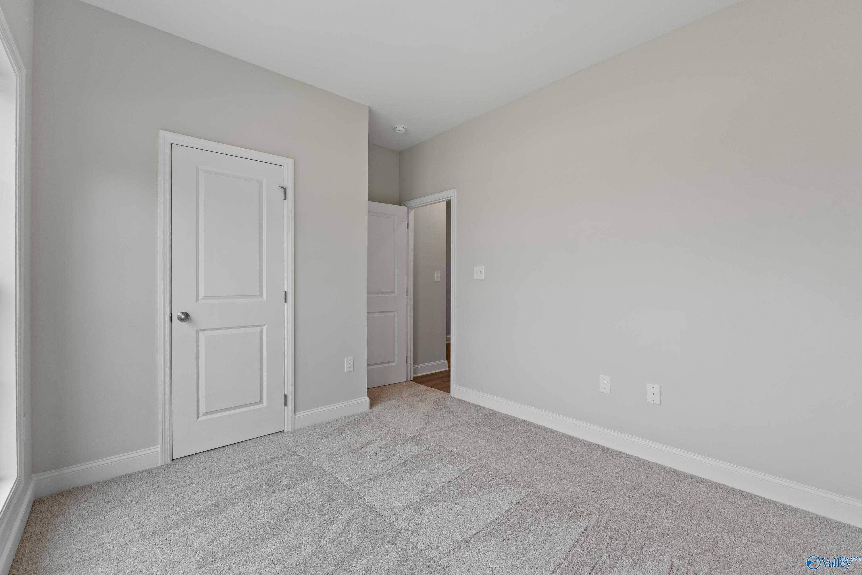 Bright secondary bedroom with gray walls, white doors, and carpet flooring in Davidson Homes The Asheville C, Huntsville, AL