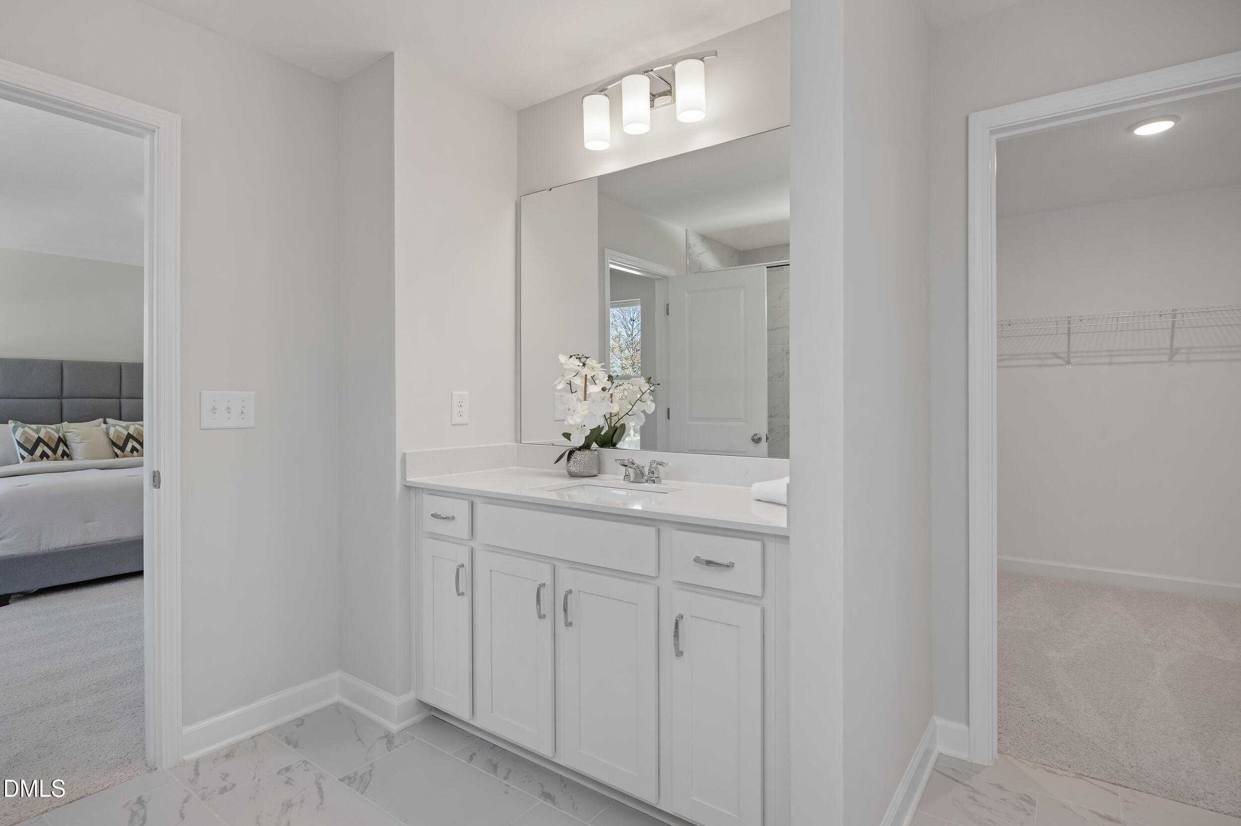 Elegant master bathroom featuring white double vanity, large mirror, and orchids in Davidson Homes The Preston C, Lillington, NC