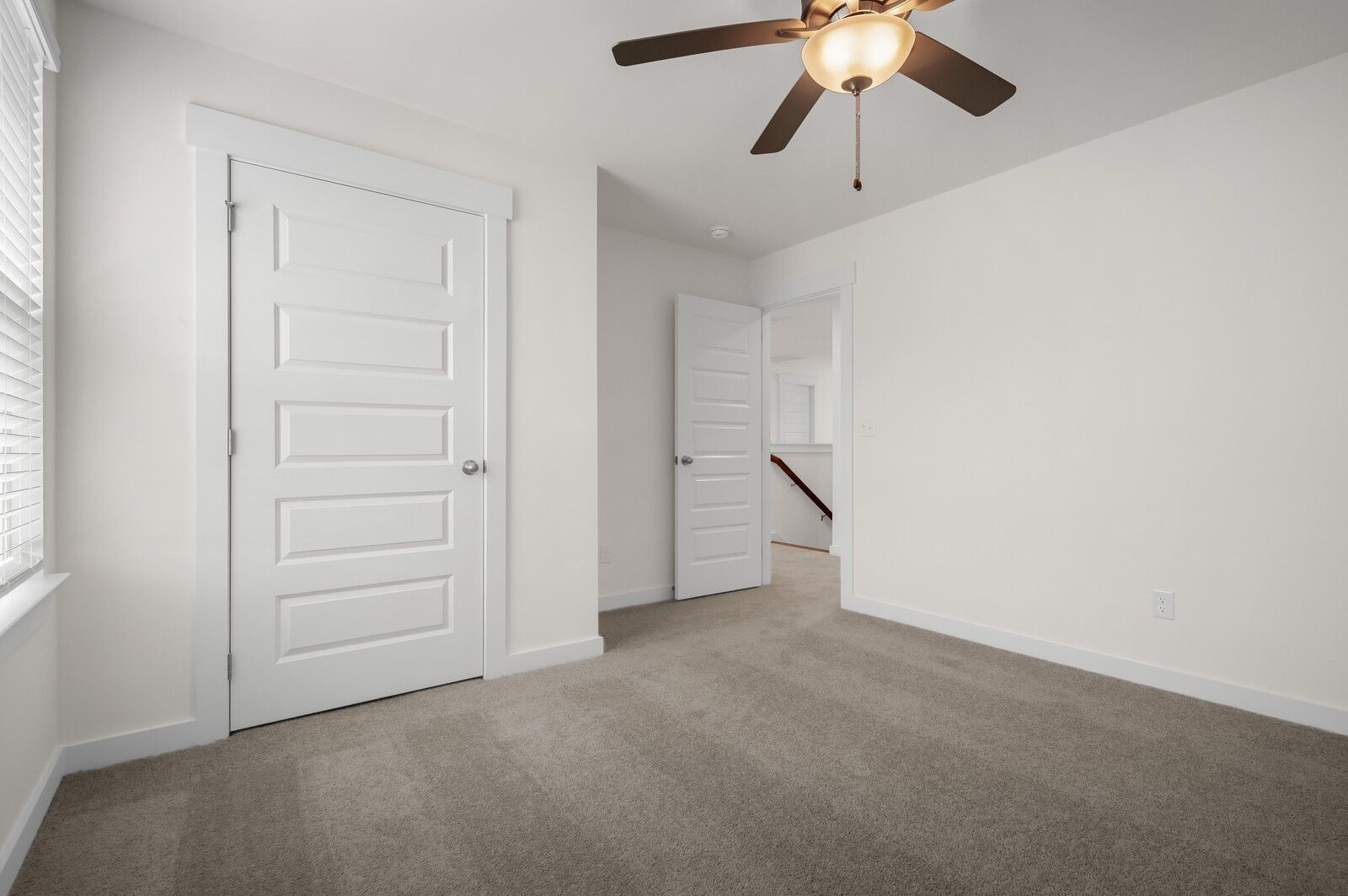 Bright, carpeted bedroom with ceiling fan in The Ash A floor plan at Woods Crossing, Gallatin, Tennessee.
