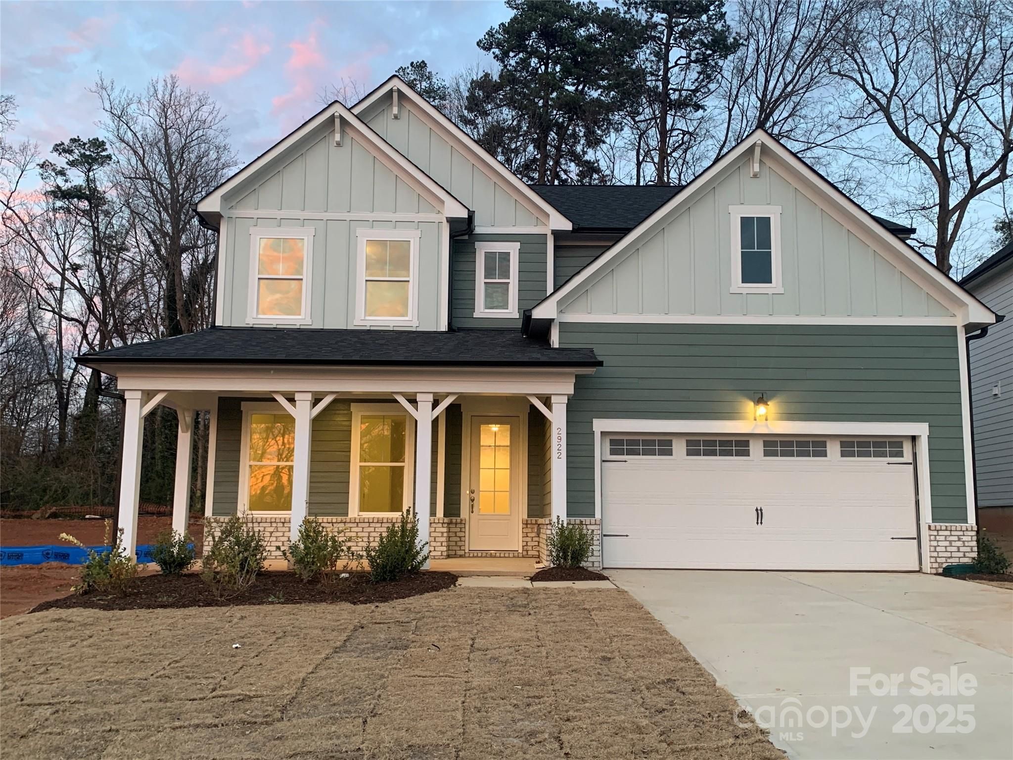 Two-story Hickory E II home by Davidson Homes: sage green siding, covered front porch, two-car garage in Enclave at Belmont, NC