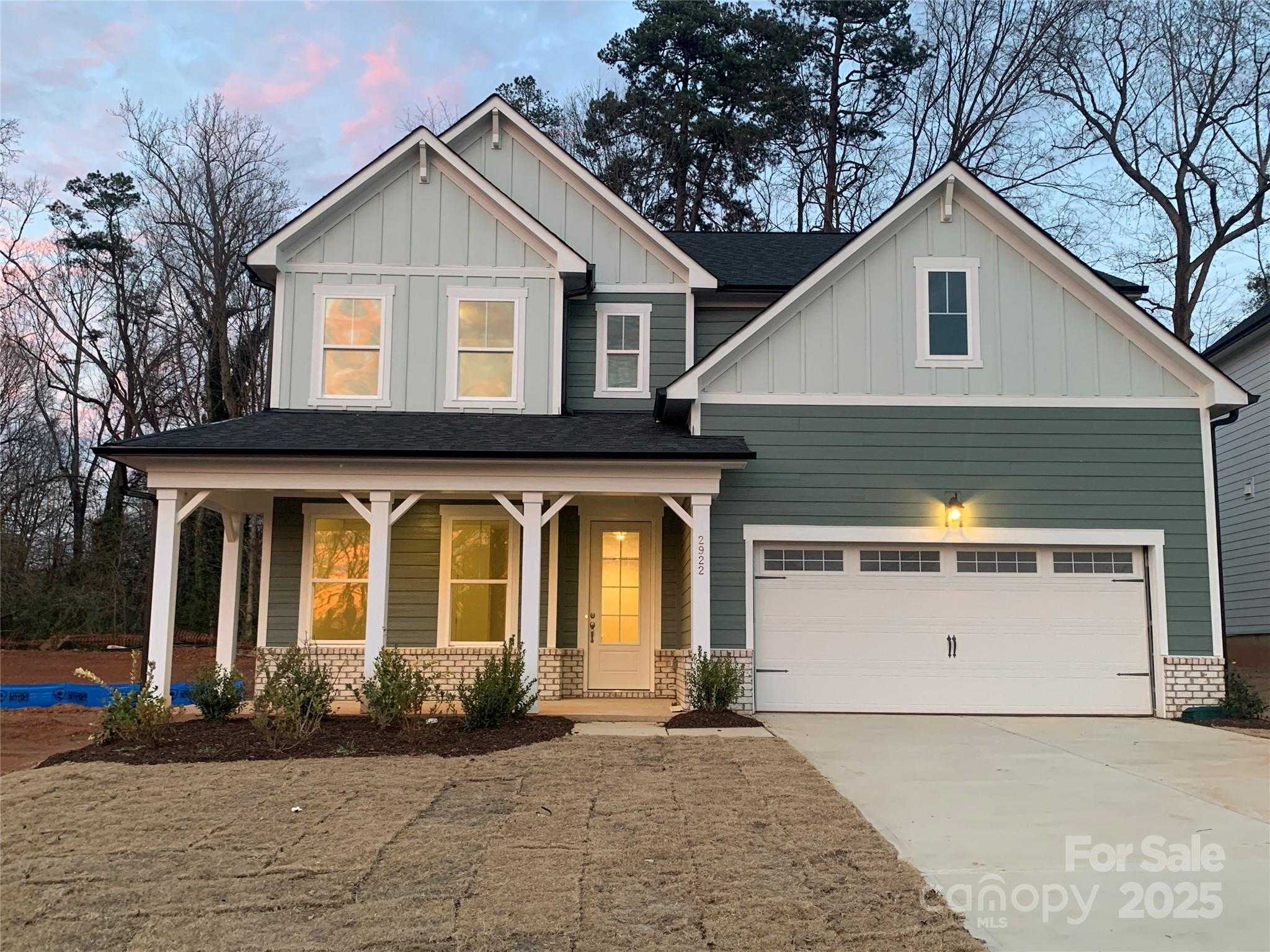 Two-story Hickory E II home by Davidson Homes: sage green siding, covered front porch, two-car garage in Enclave at Belmont, NC