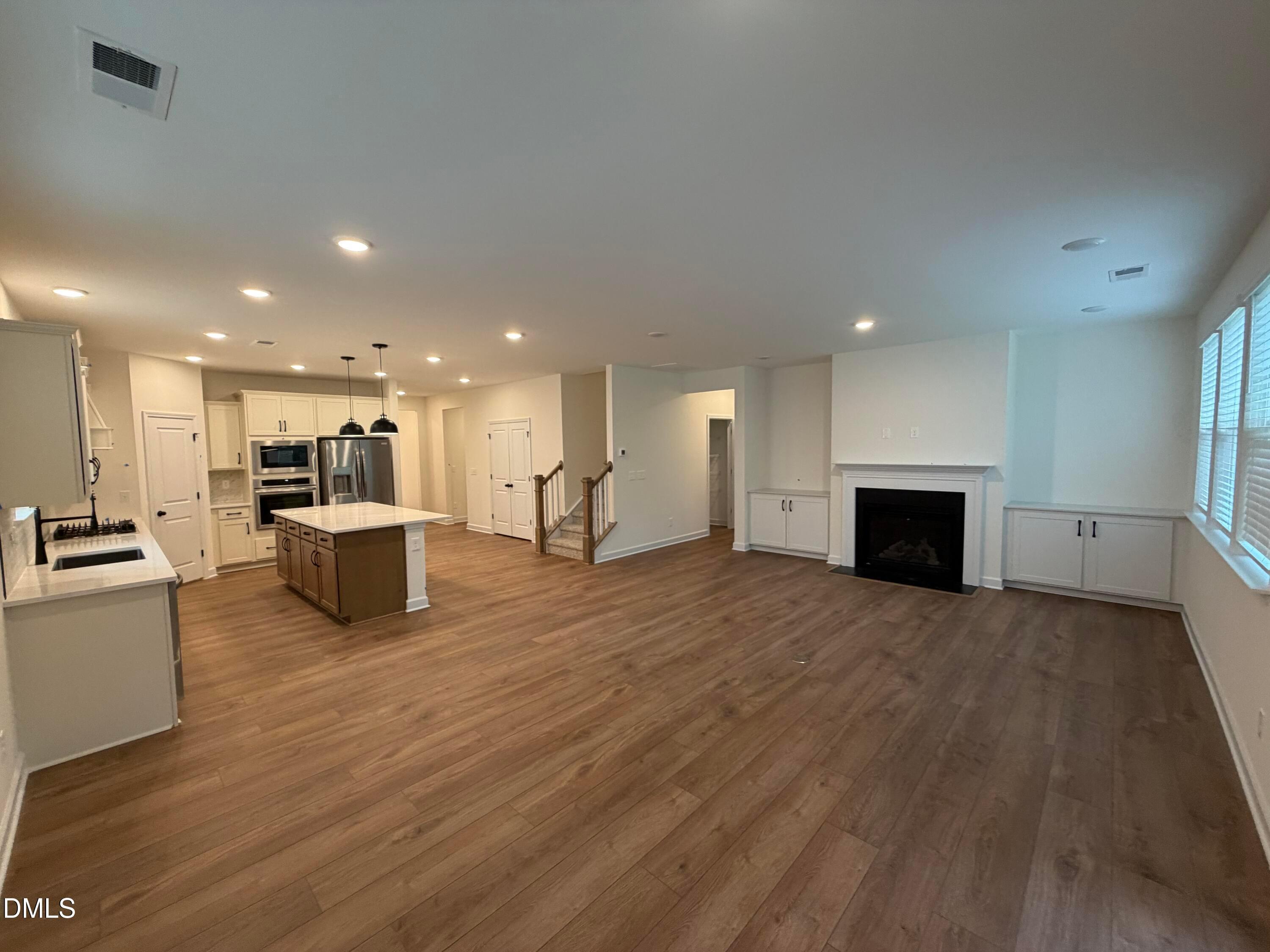 Open-concept living room with fireplace and kitchen island in Davidson Homes The Ashport M floor plan, Wendell Ridge, NC
