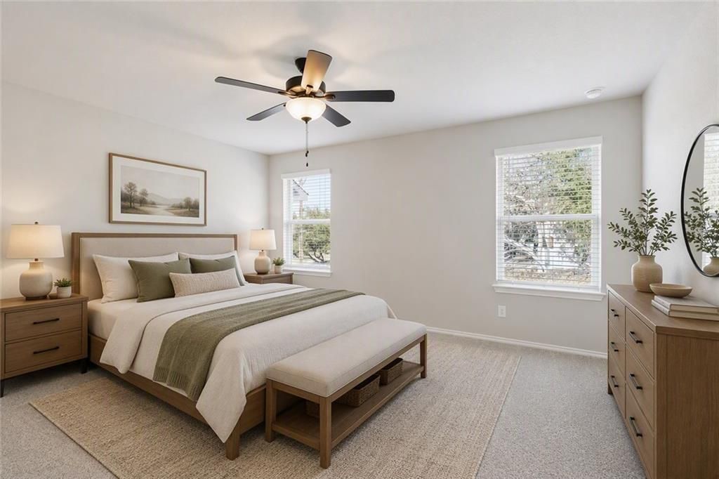 Bright primary bedroom with ceiling fan, upholstered bed, and wood dresser in Davidson Homes The Charlotte B, Cartersville, GA